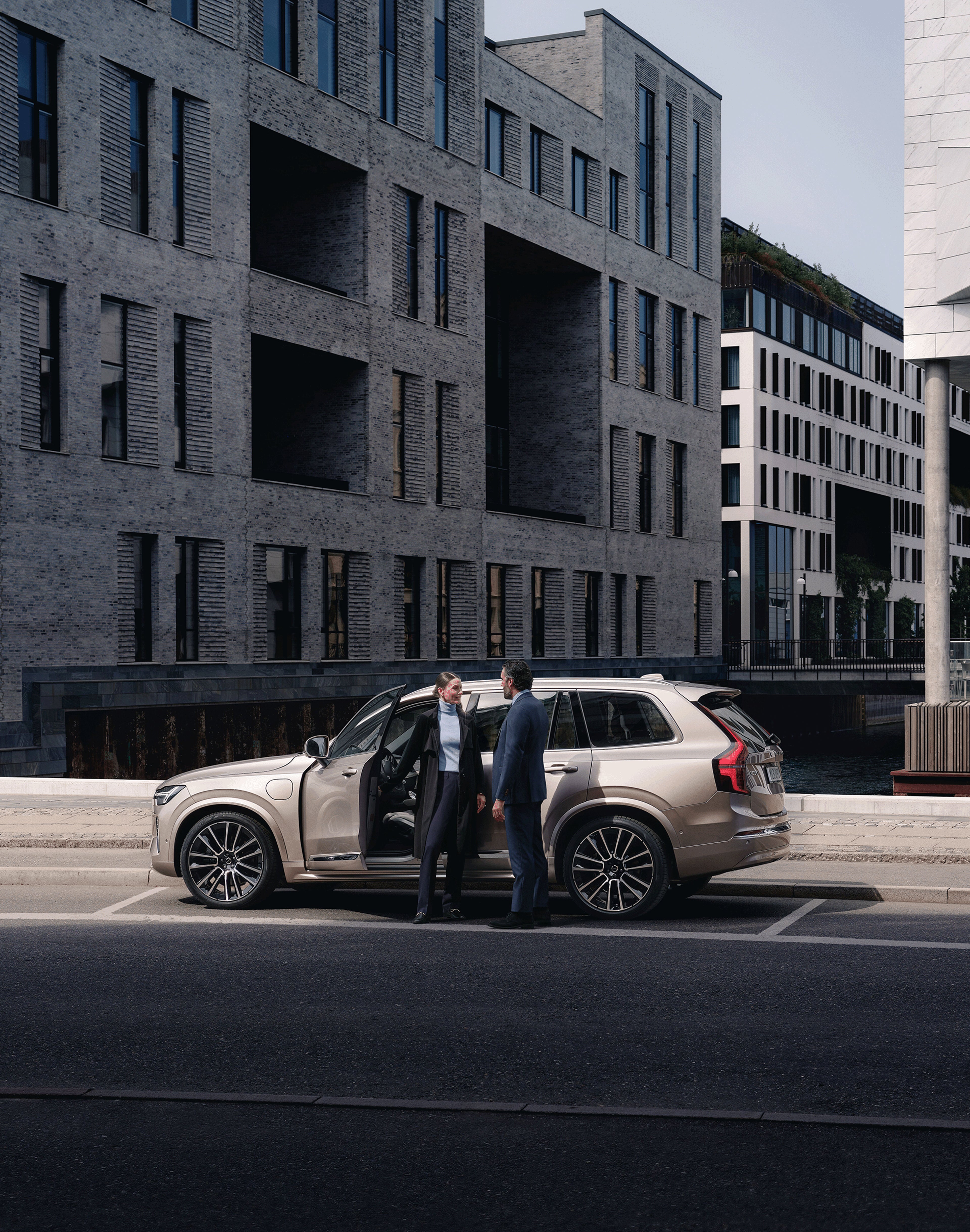 Zwei Menschen vor einem Volvo XC90 Plug-in Hybrid.