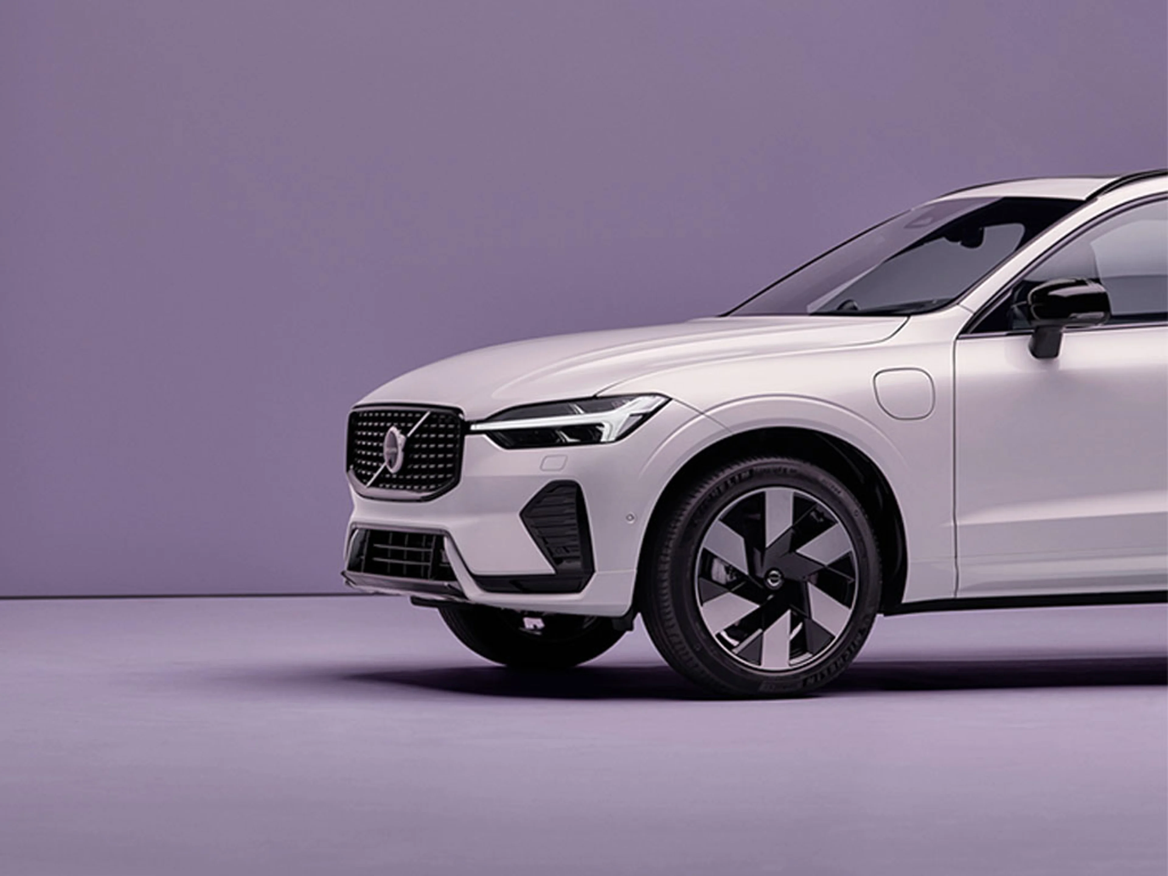 Vue partielle d’un SUV Volvo blanc dans une pièce minimaliste violette.