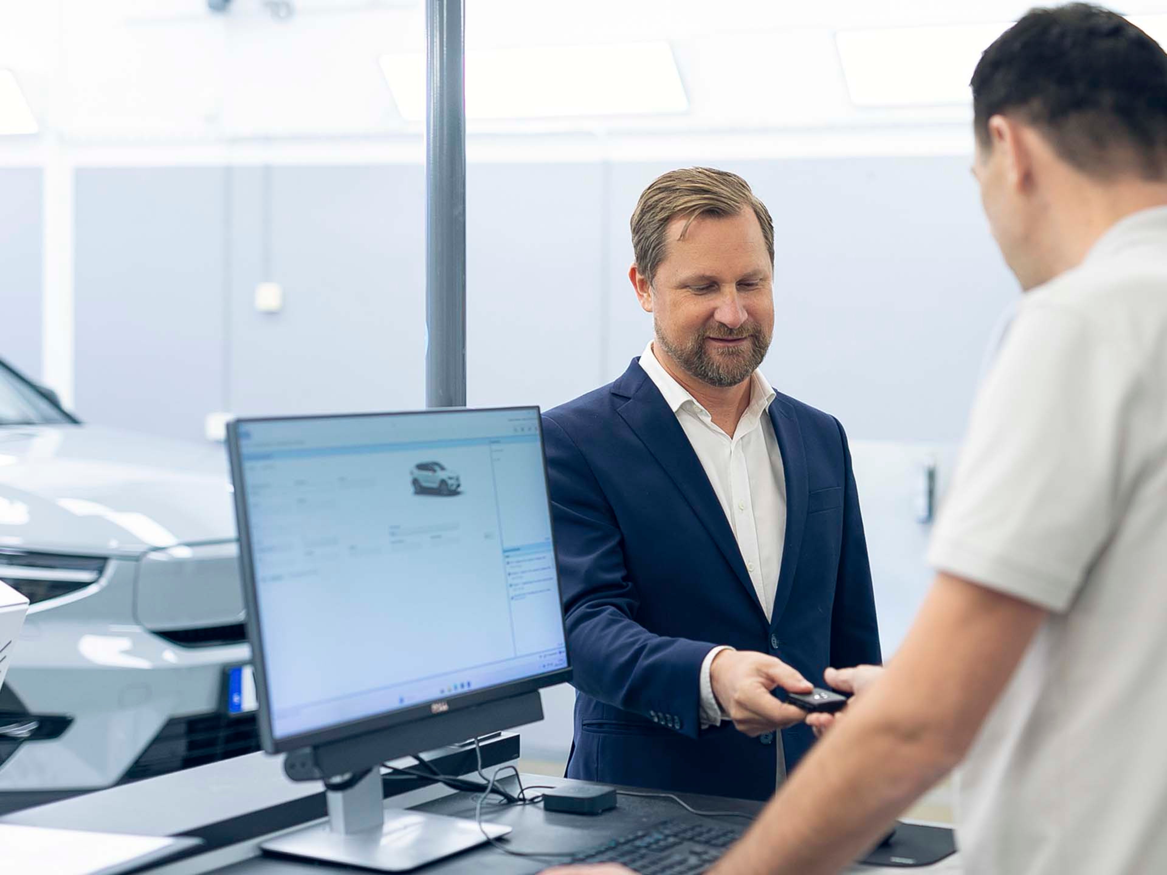 Un hombre entregando sus llaves de su vehículo Volvo en la recepción del servicio oficial Volvo para su mantenimiento