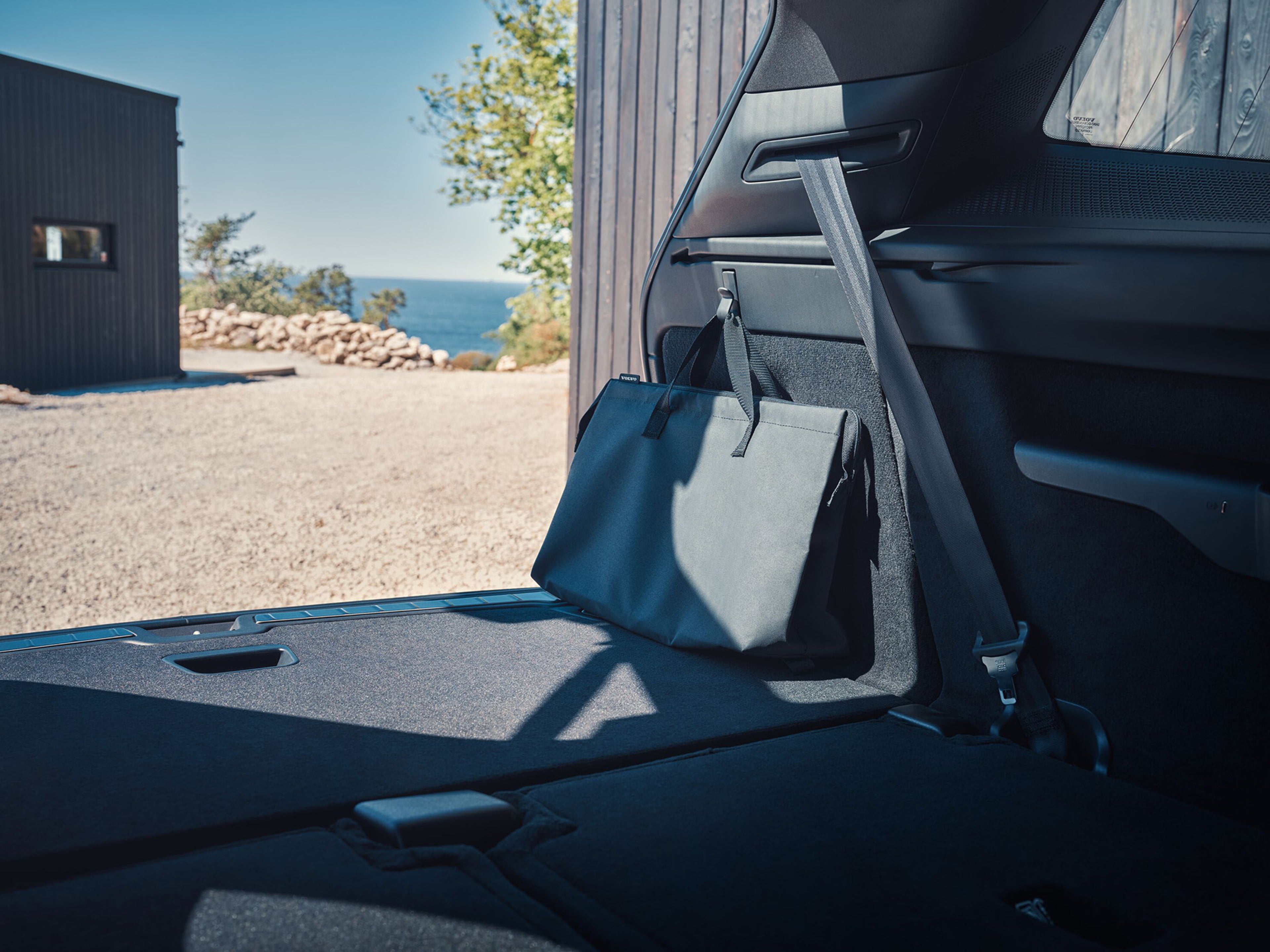 Bagageira aberta com destaque para o saco do cabo de carregamento preso num dos ganchos.