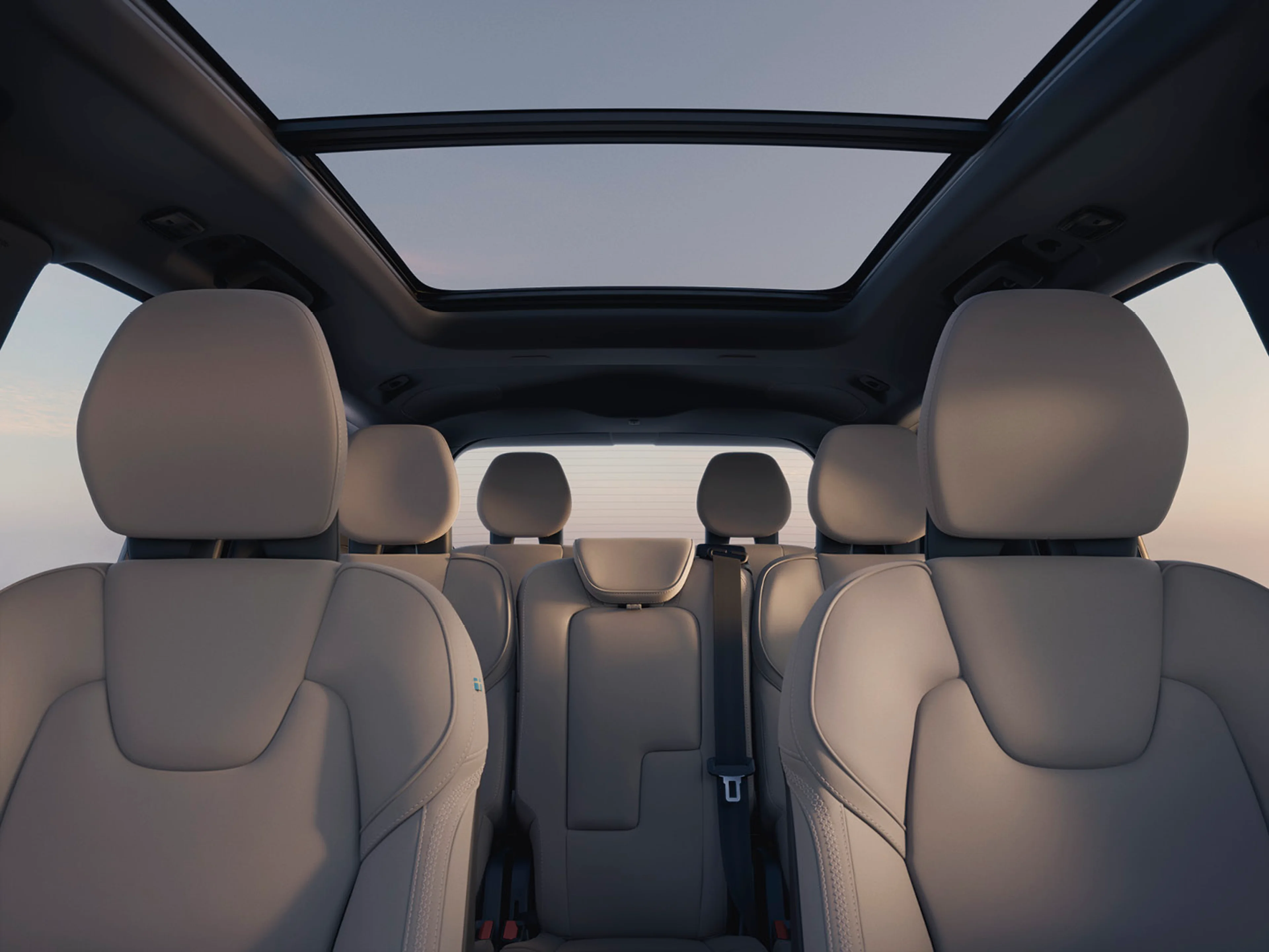 Volvo XC90 bokiem, obok stojąca kobieta oraz mężczyzna przy otwartym bagażniku, w tle morze
