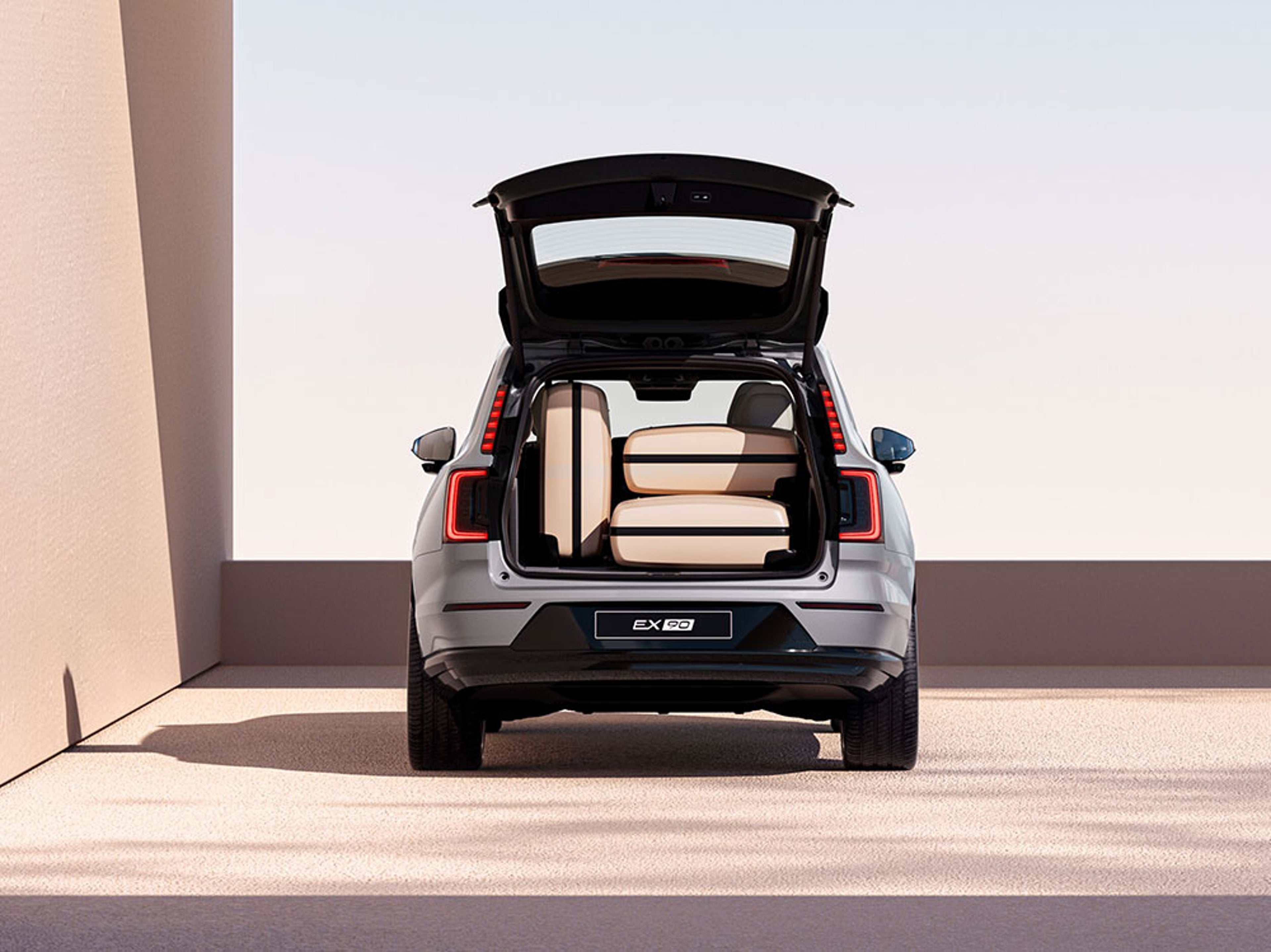 SUV électrique gris vu de l’arrière, coffre ouvert, montrant l’espace de chargement avec plusieurs valises