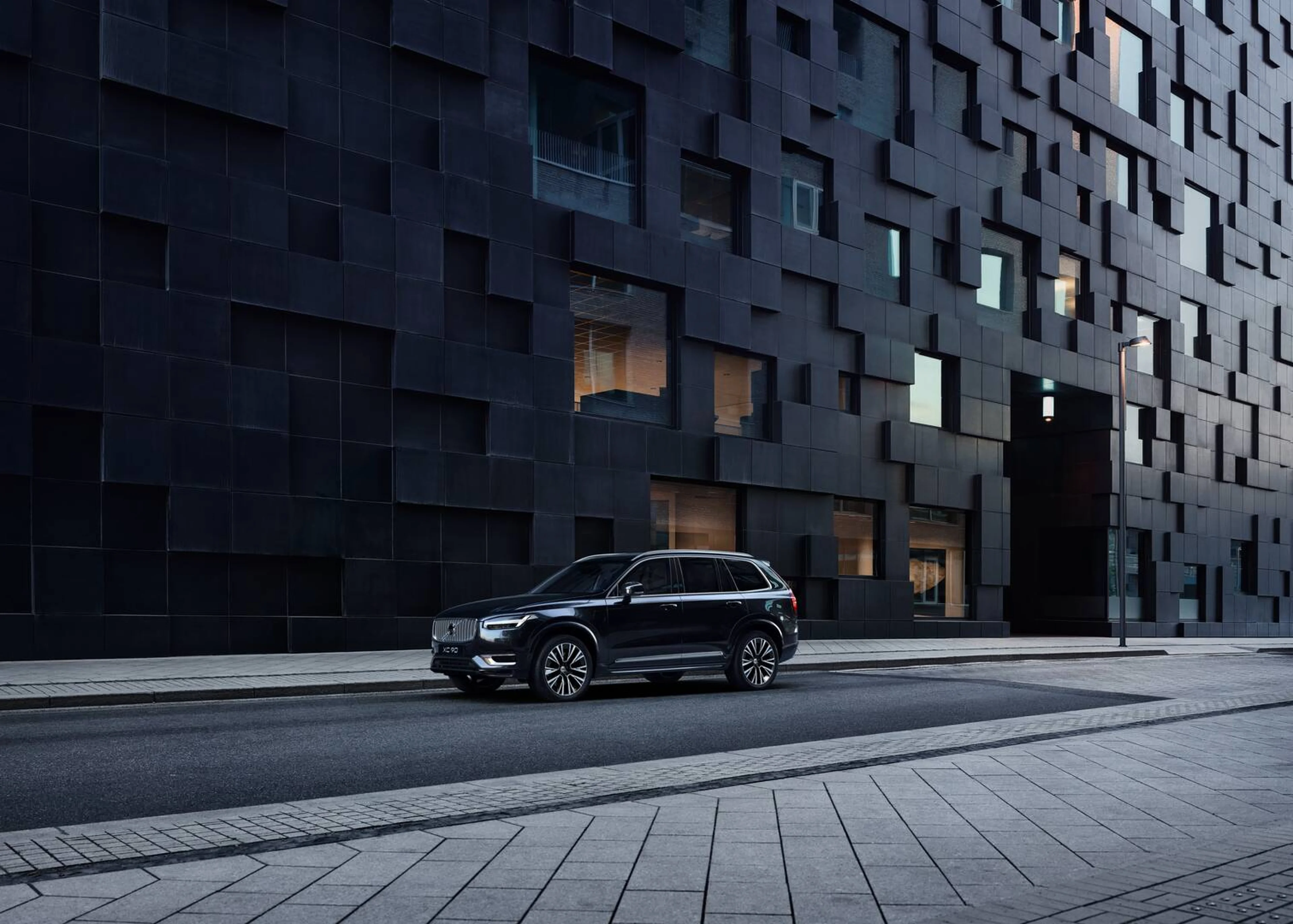 En stor bil fra Volvo ses forfra fra siden kørende i et bymiljø