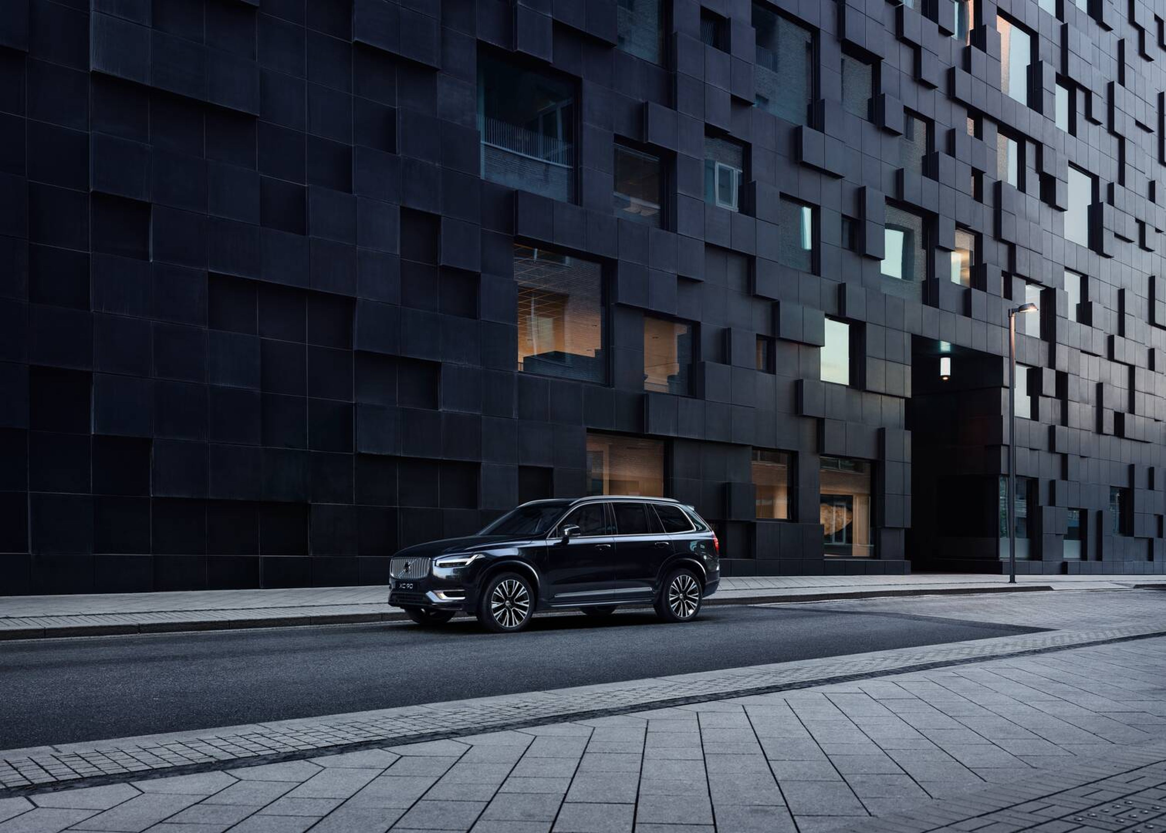 En stor bil fra Volvo ses forfra fra siden kørende i et bymiljø