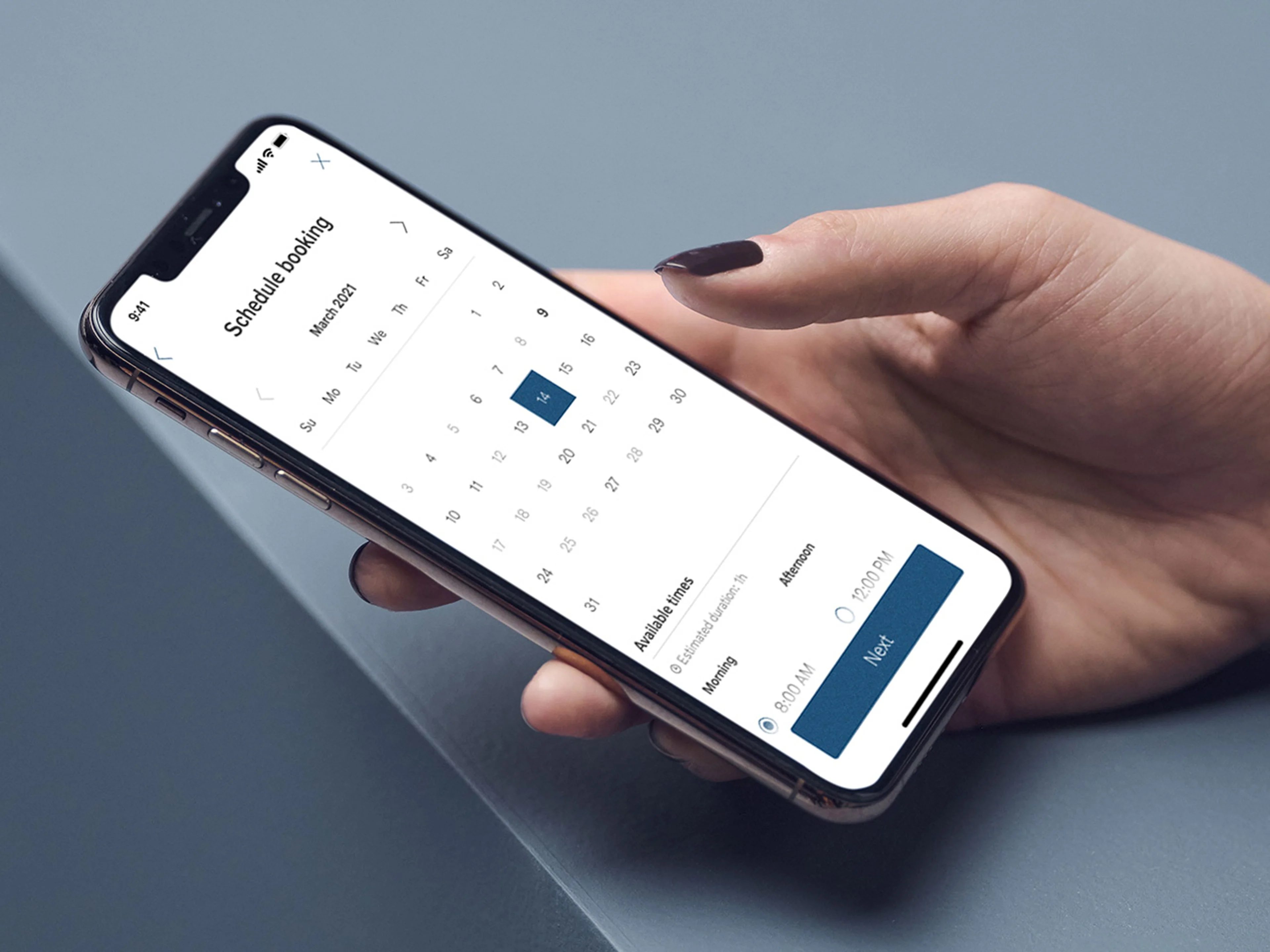 A hand holding a smartphone displaying a scheduling Volvo cars app with a calendar view for March and available booking times.