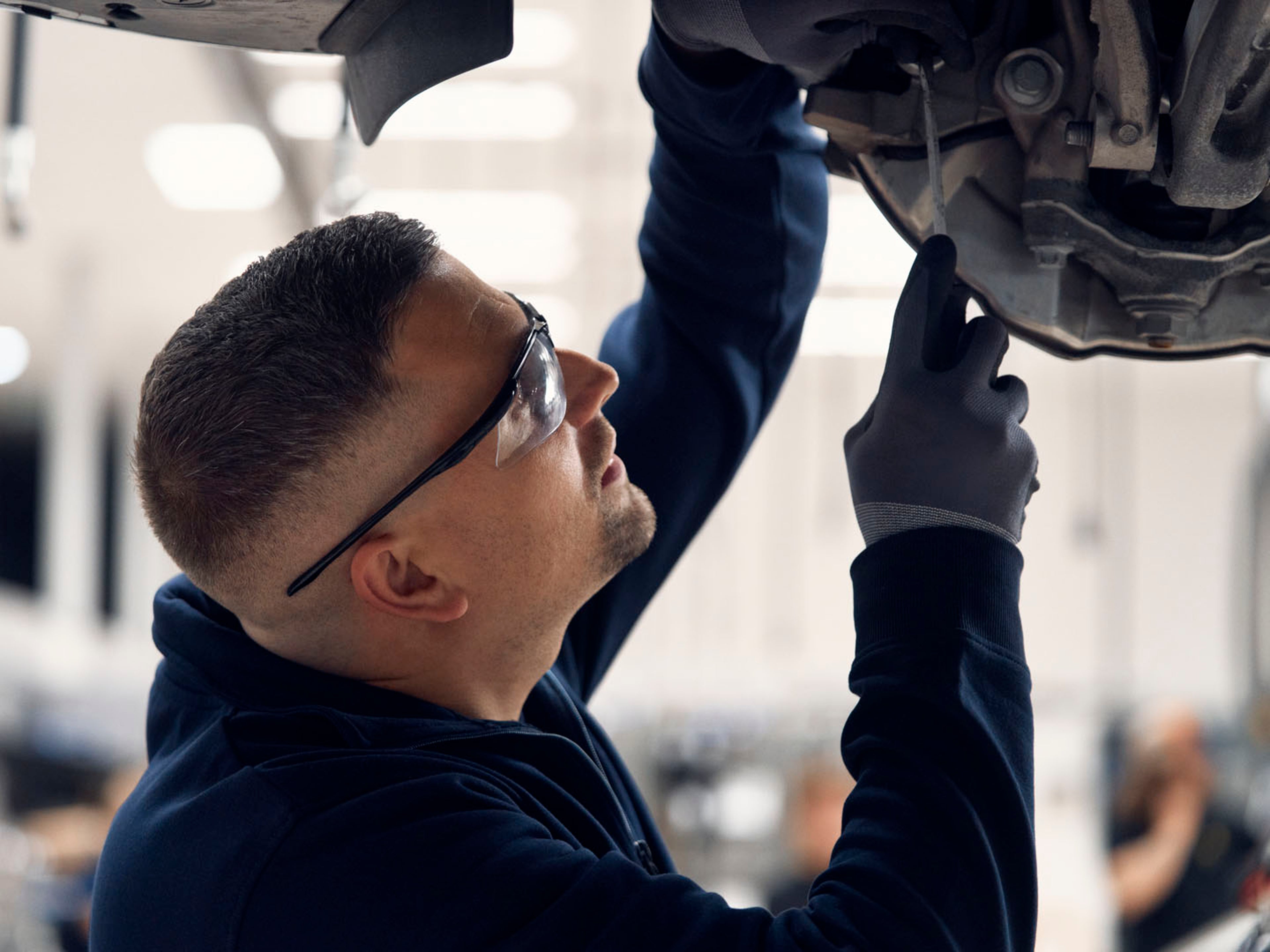 Un mecánico revisando el bajo de un vehículo Volvo