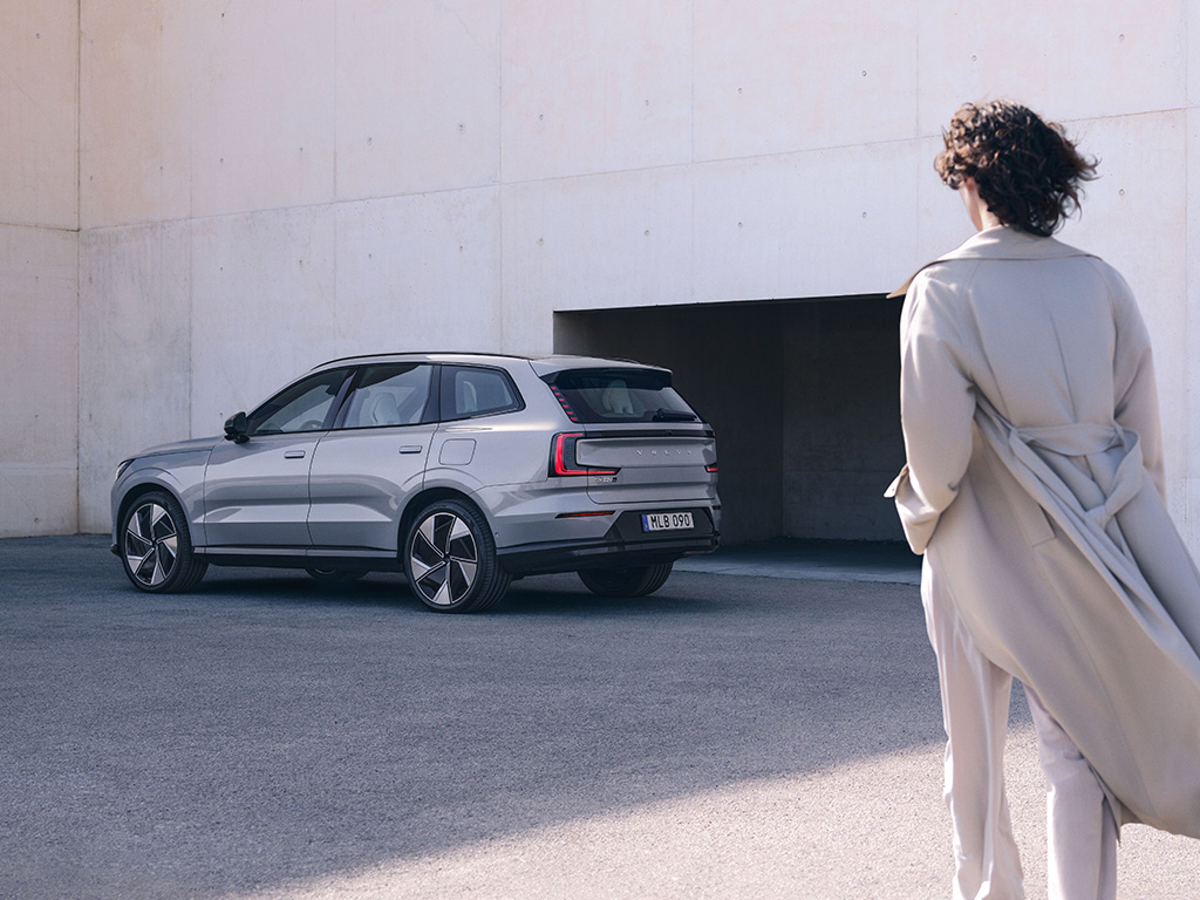 Eine Frau läuft auf einen Volvo EX90 zu.