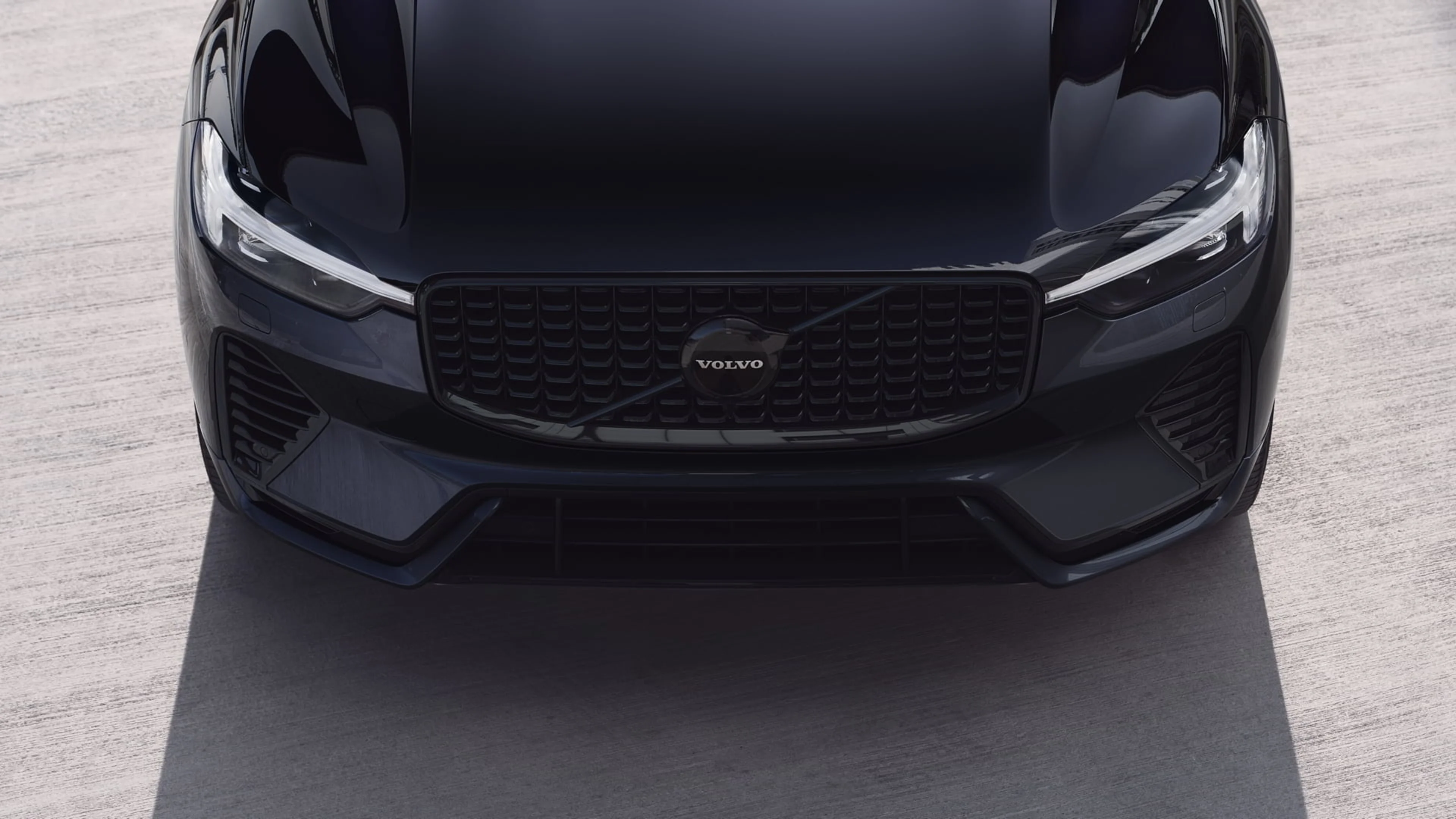 Vue avant d’une Volvo Black Edition avec calandre et logo visibles, stationnée sur une surface en béton