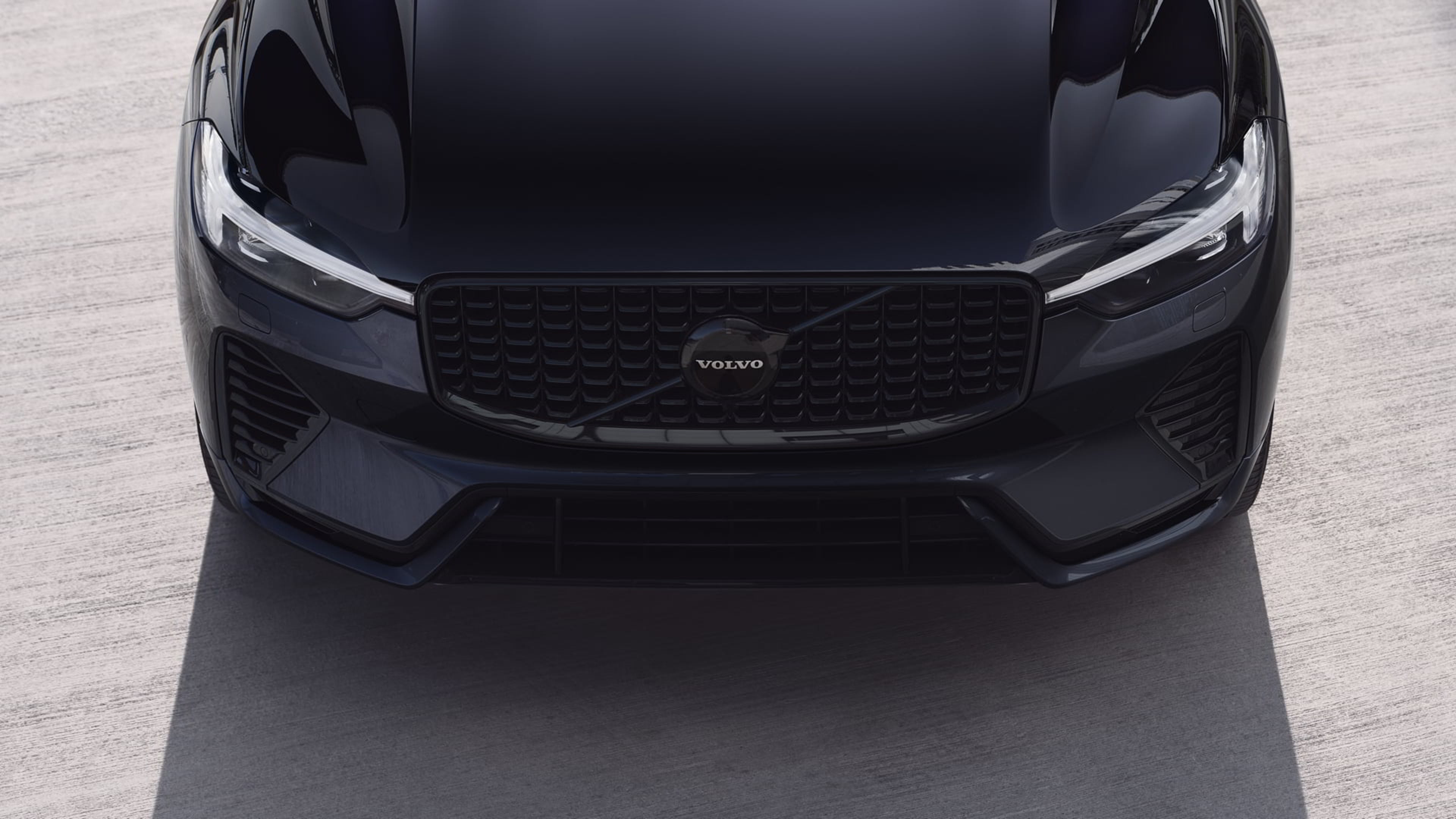 Vue avant du Volvo XC60 Black Edition, calandre sport avec logo central, phares LED effilés et capot aux lignes puissantes.