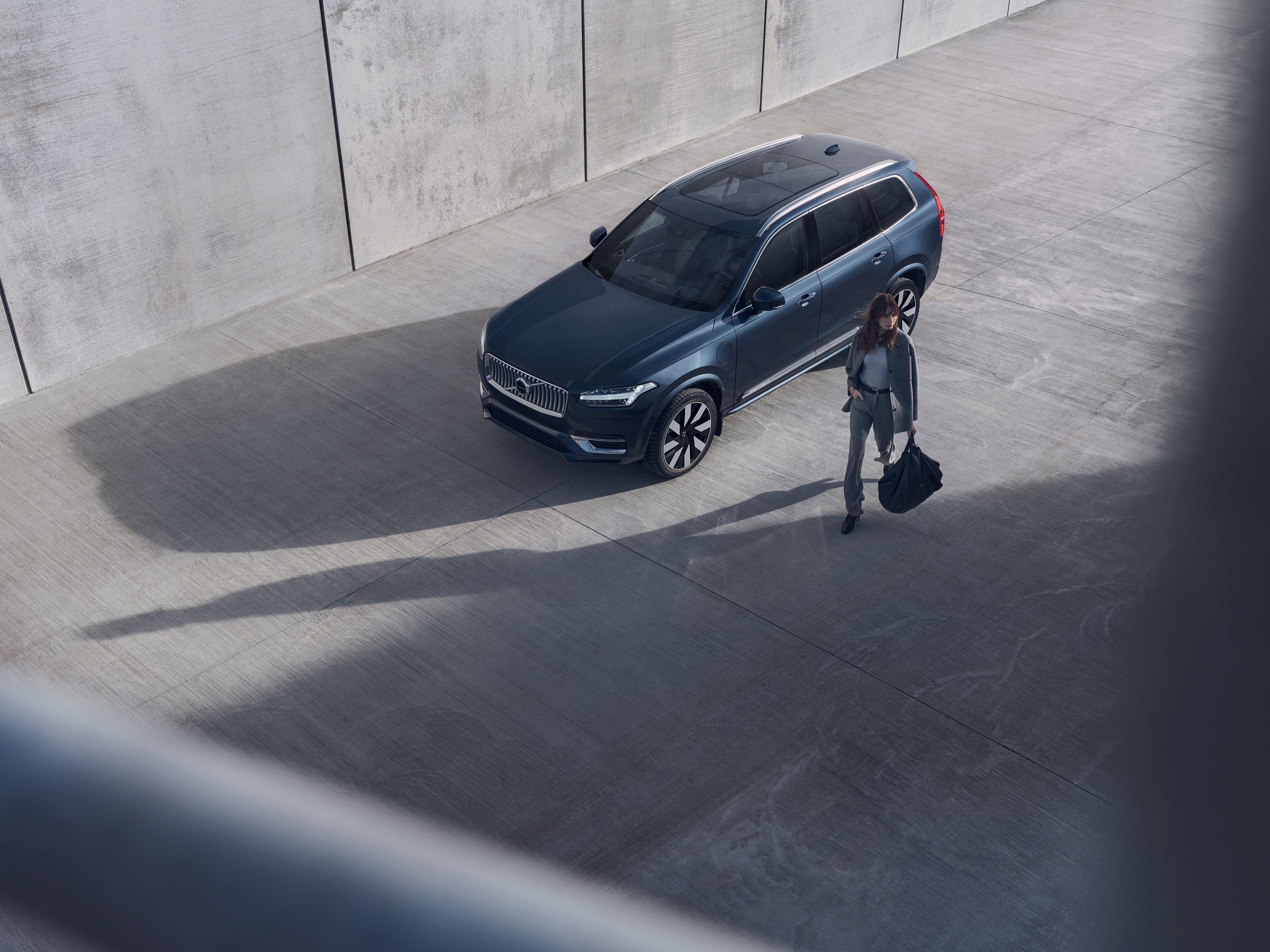 Kobieta przy Volvo XC90 obok budynku, pokazane z lotu ptaka