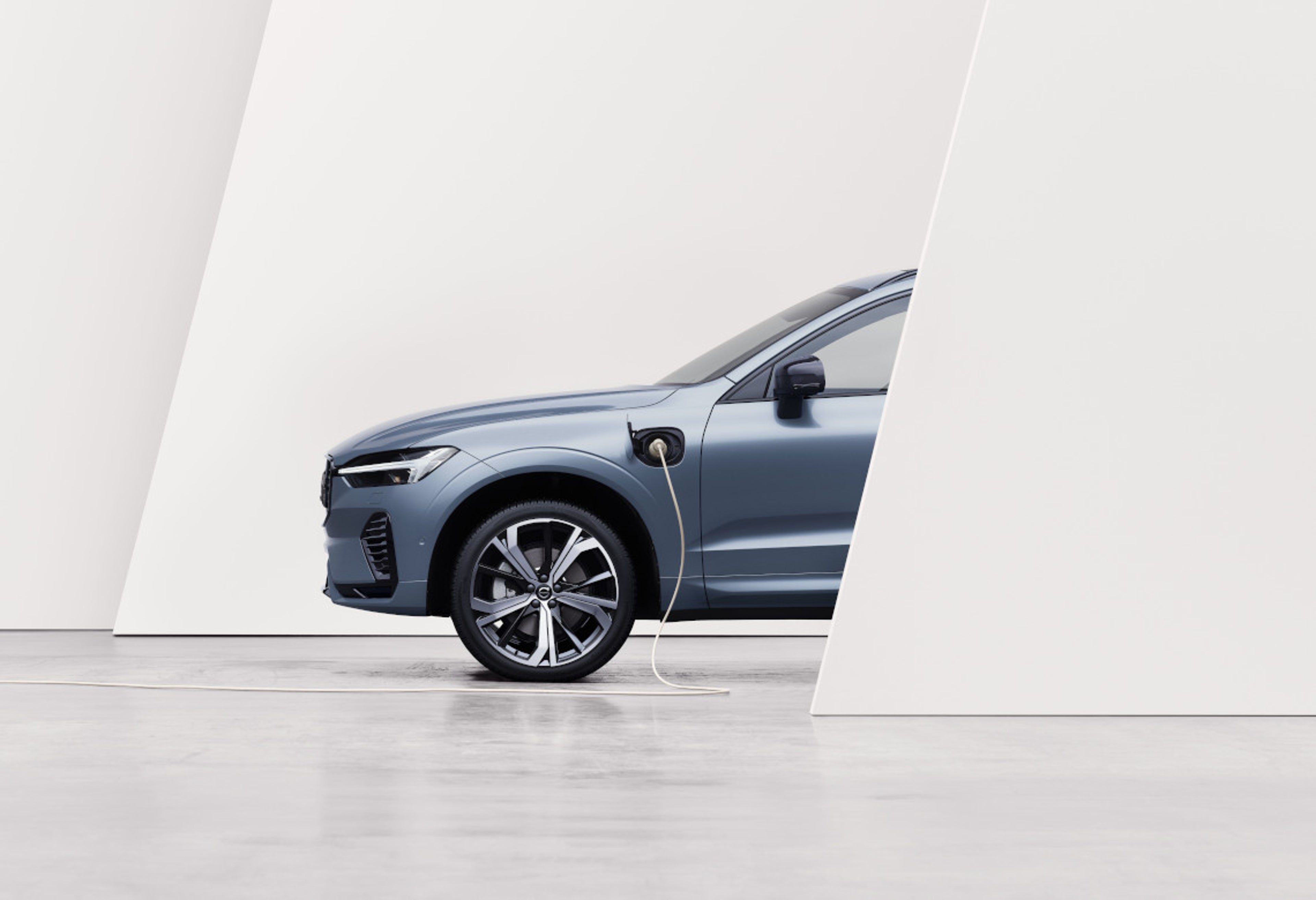 Volvo S90 Recharge steht halb verdeckt hinter einer Wand und lädt