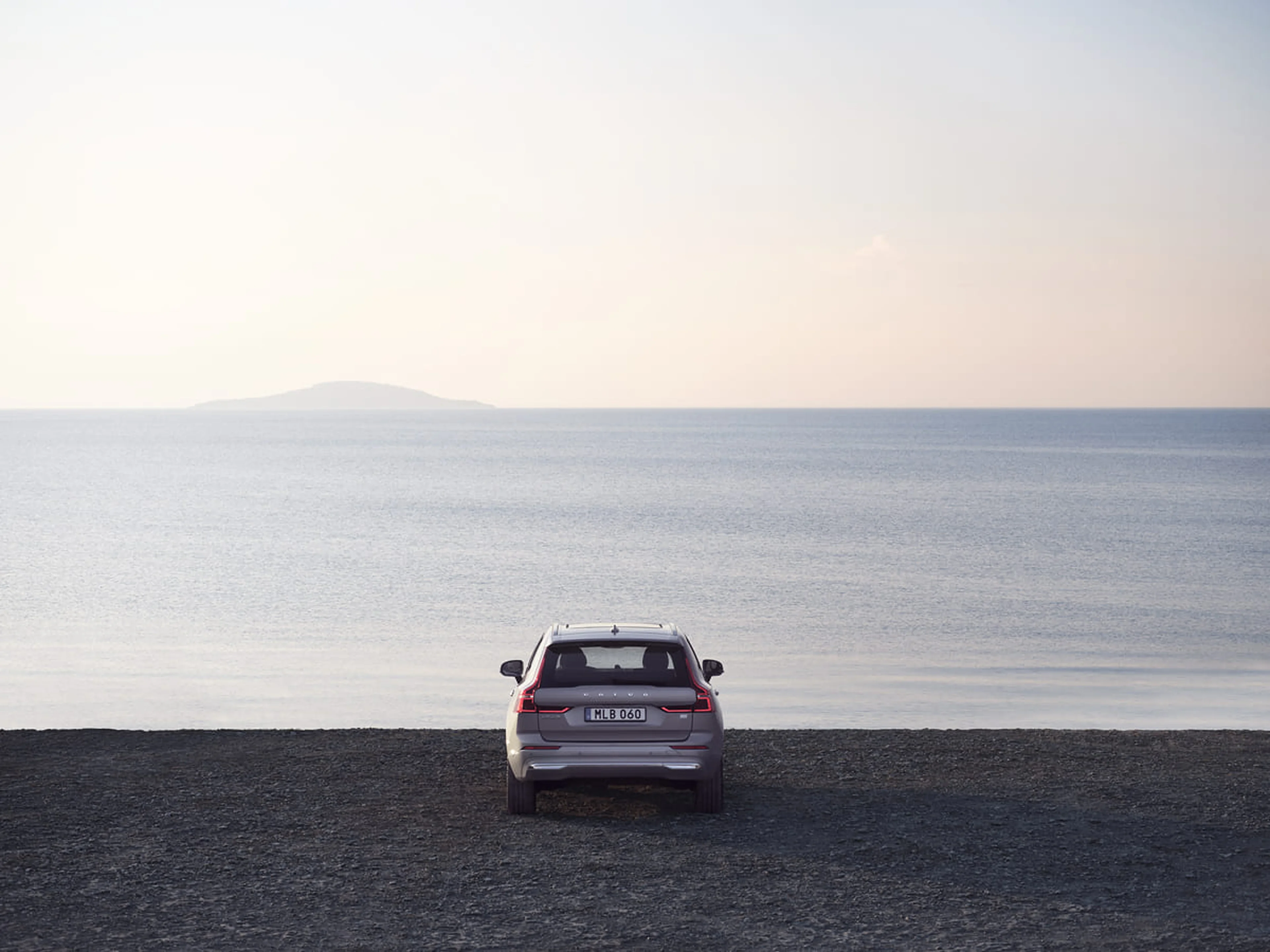 Volvo som står på grönt gräs, vid kust linje och pekar med fronten mot havet och horisonten