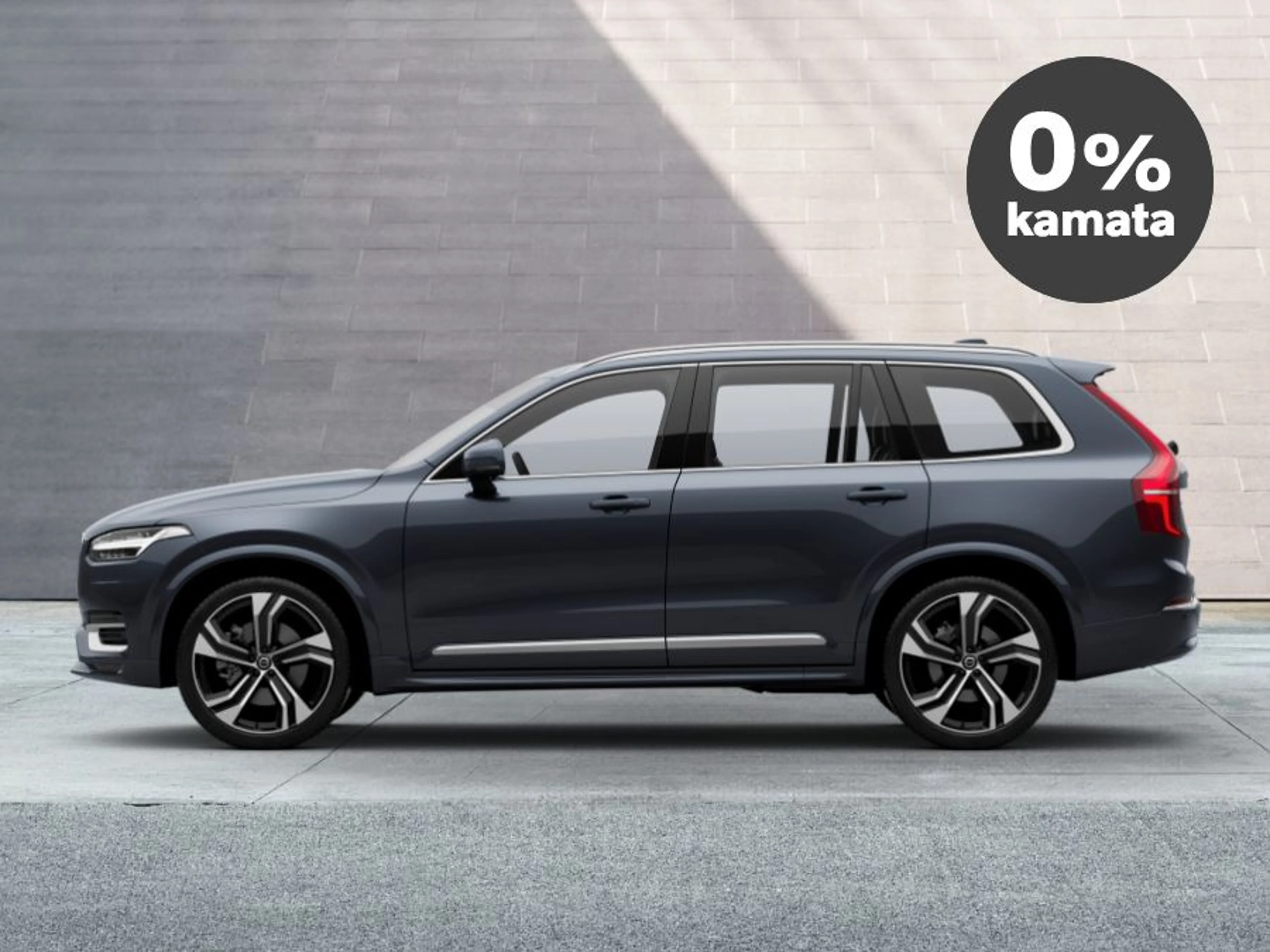 Volvo XC90 parkiran ispred suvremene sive fasade, prikazan iz bočnog profila, s oznakom '0 % kamata' u crnom krugu u gornjem desnom kutu.