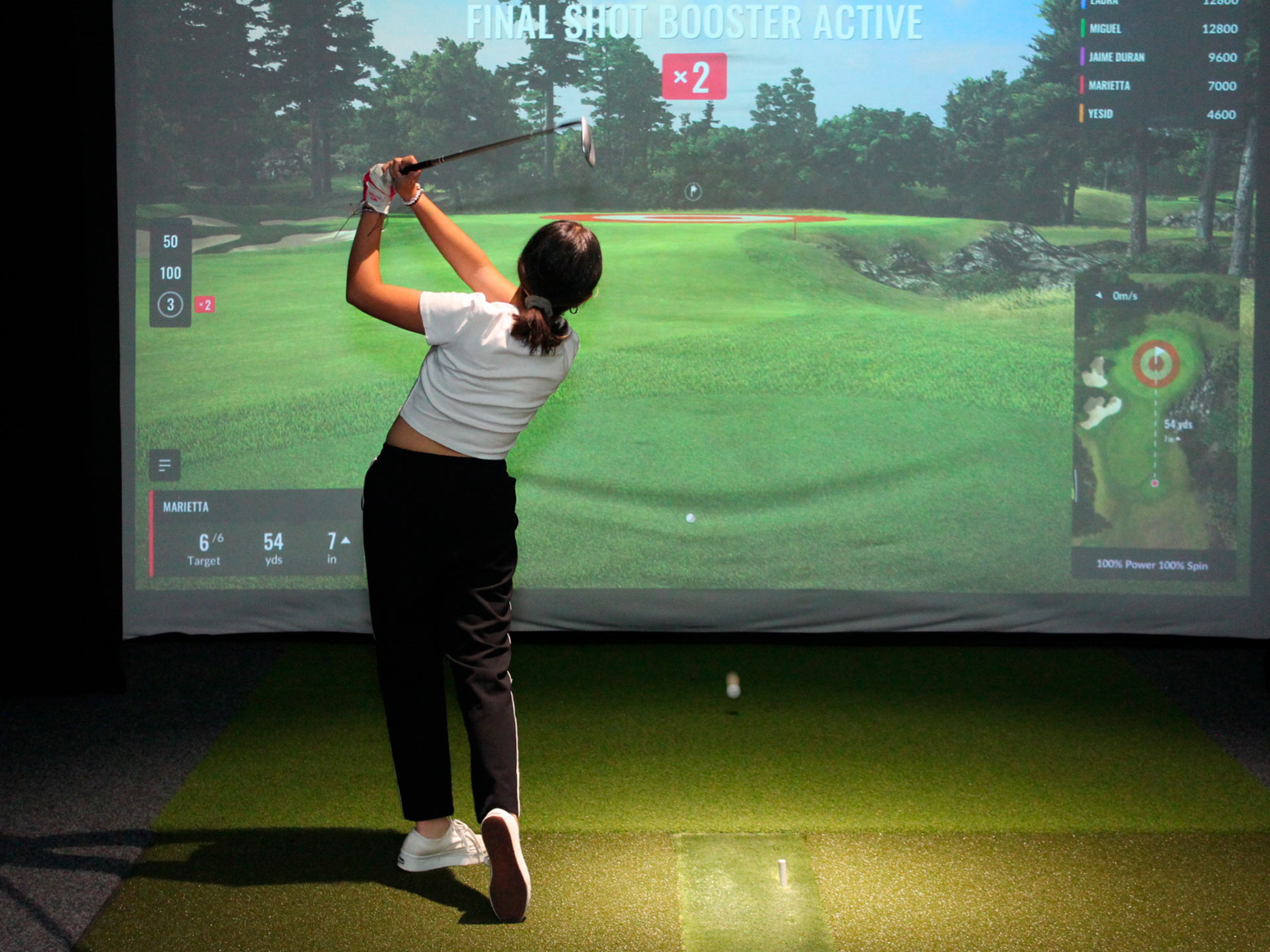 Una mujer jugando golf indoor.