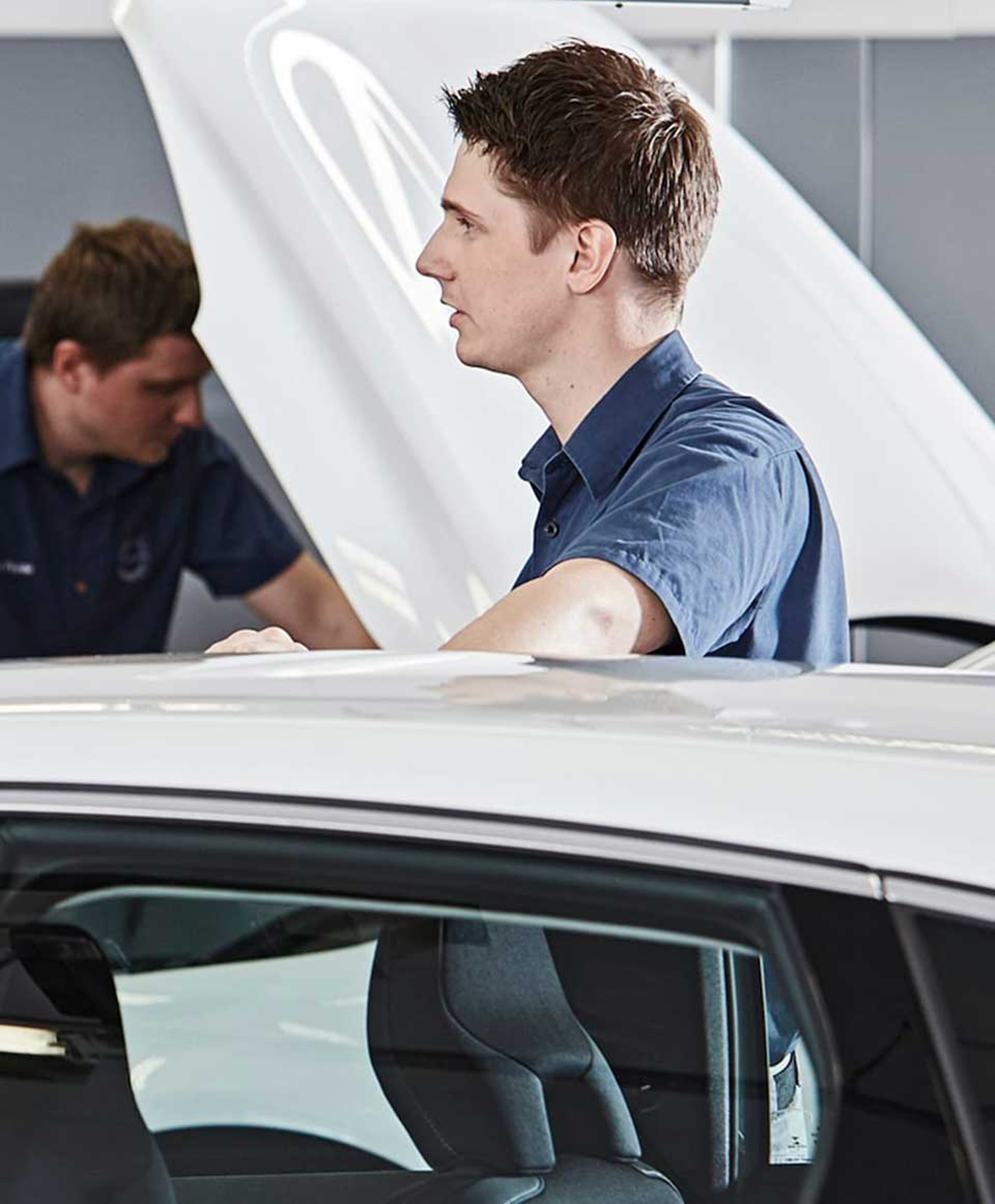 Volvo-servicemedarbejder rører ved taget på hvid bil i forbindelse med service