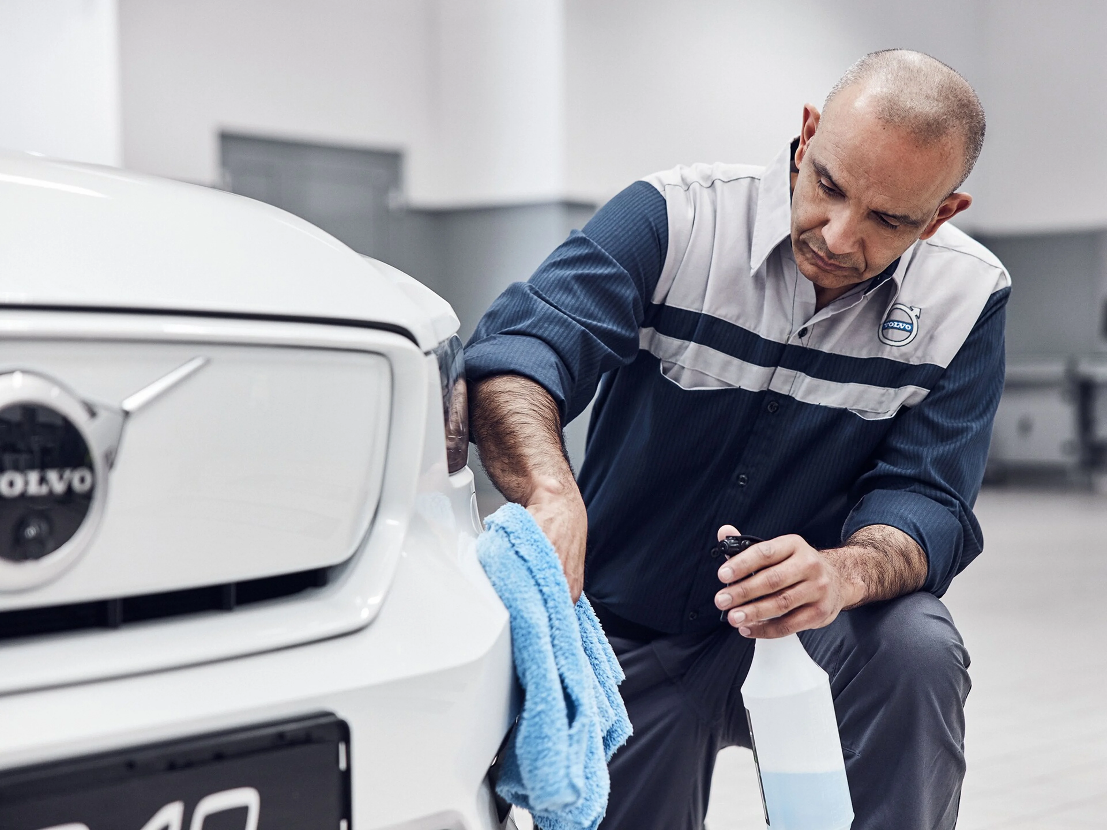 A Volvo technician cleaning down a white Volvo in the showroom.