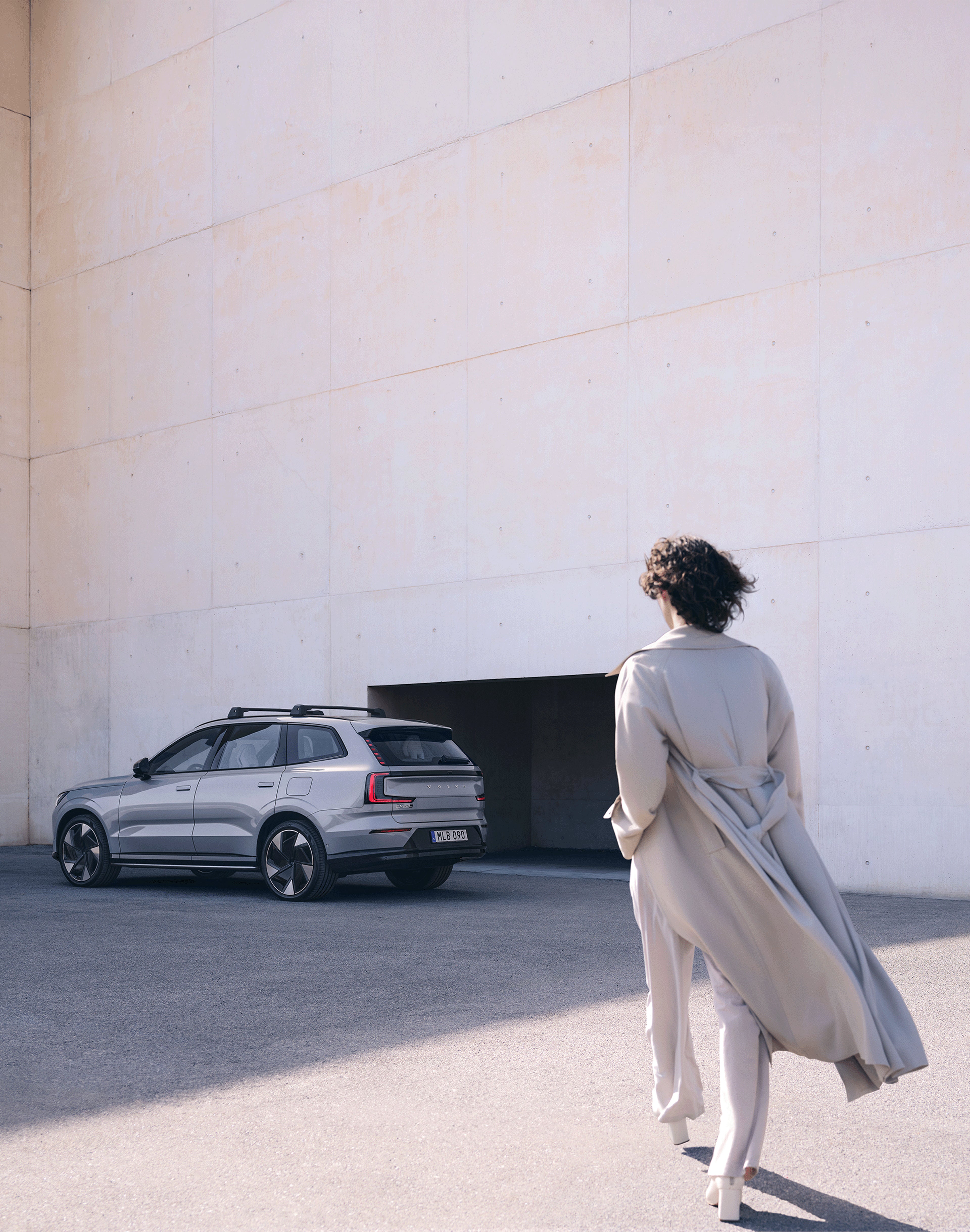 Eine Frau läuft auf einen Volvo EX90 zu.