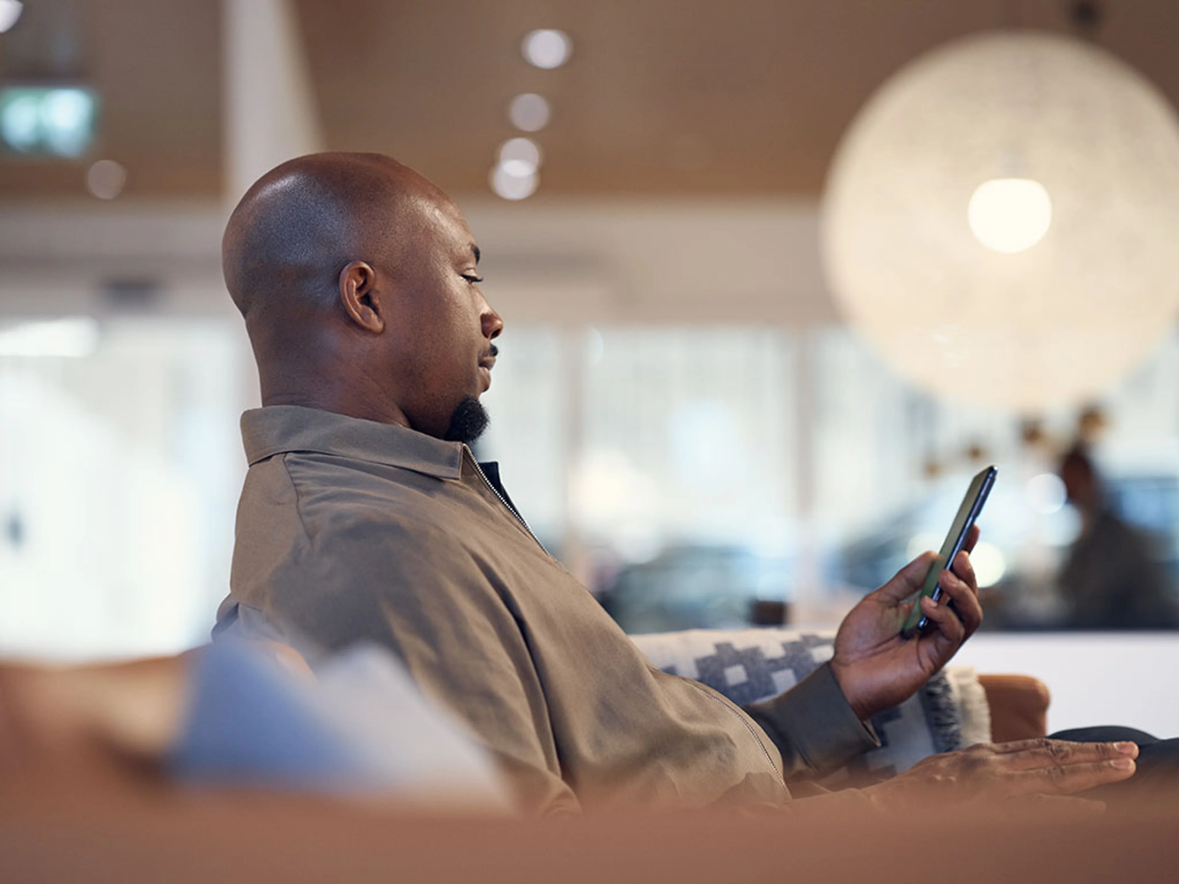 Homme tenant un smartphone à l’intérieur d’une concession Volvo moderne