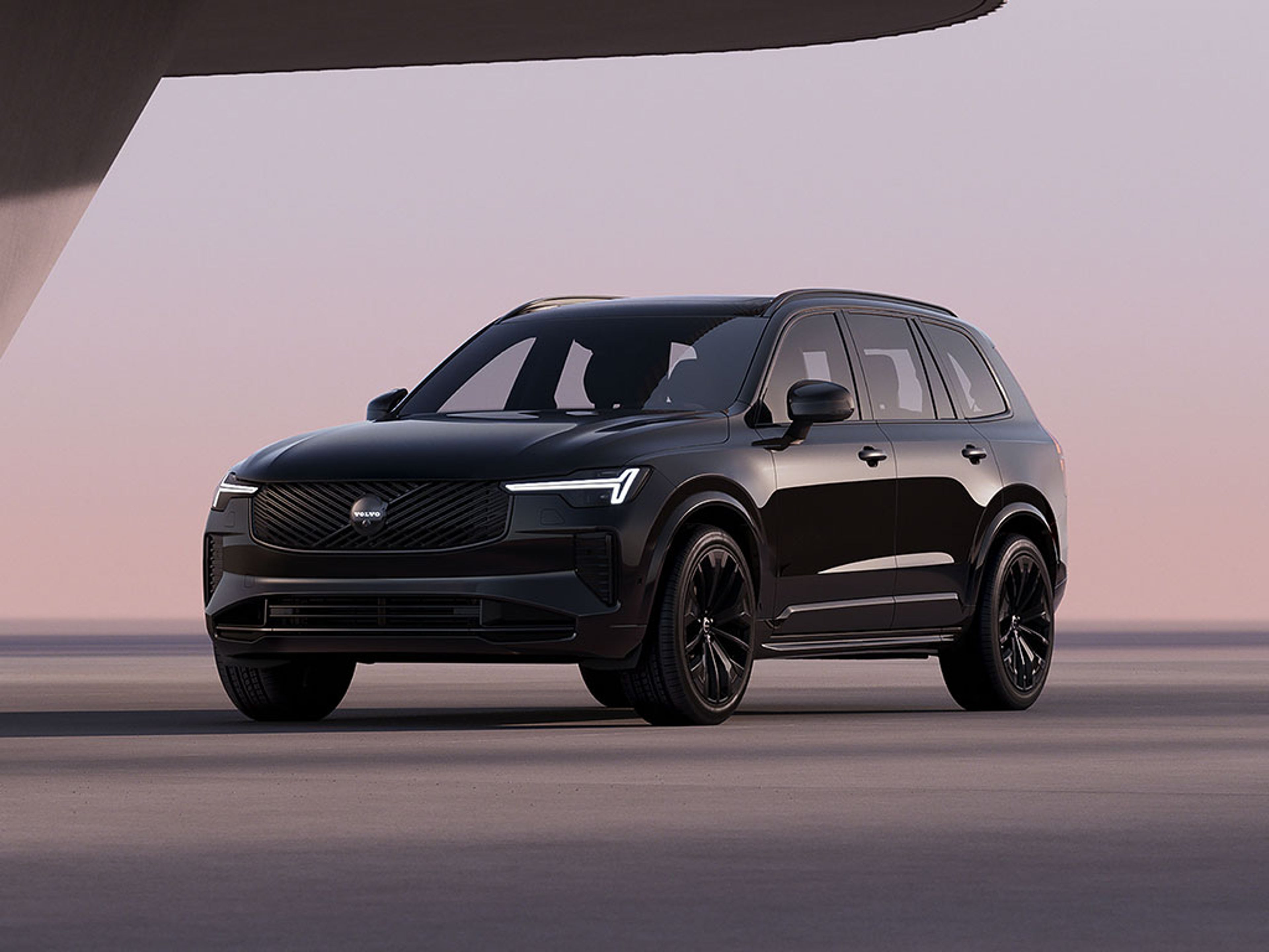 XC90 Black Edition vu de trois quart avant dans un décor moderne et minimaliste avec phares LED en forme de marteau de Thor allumés.