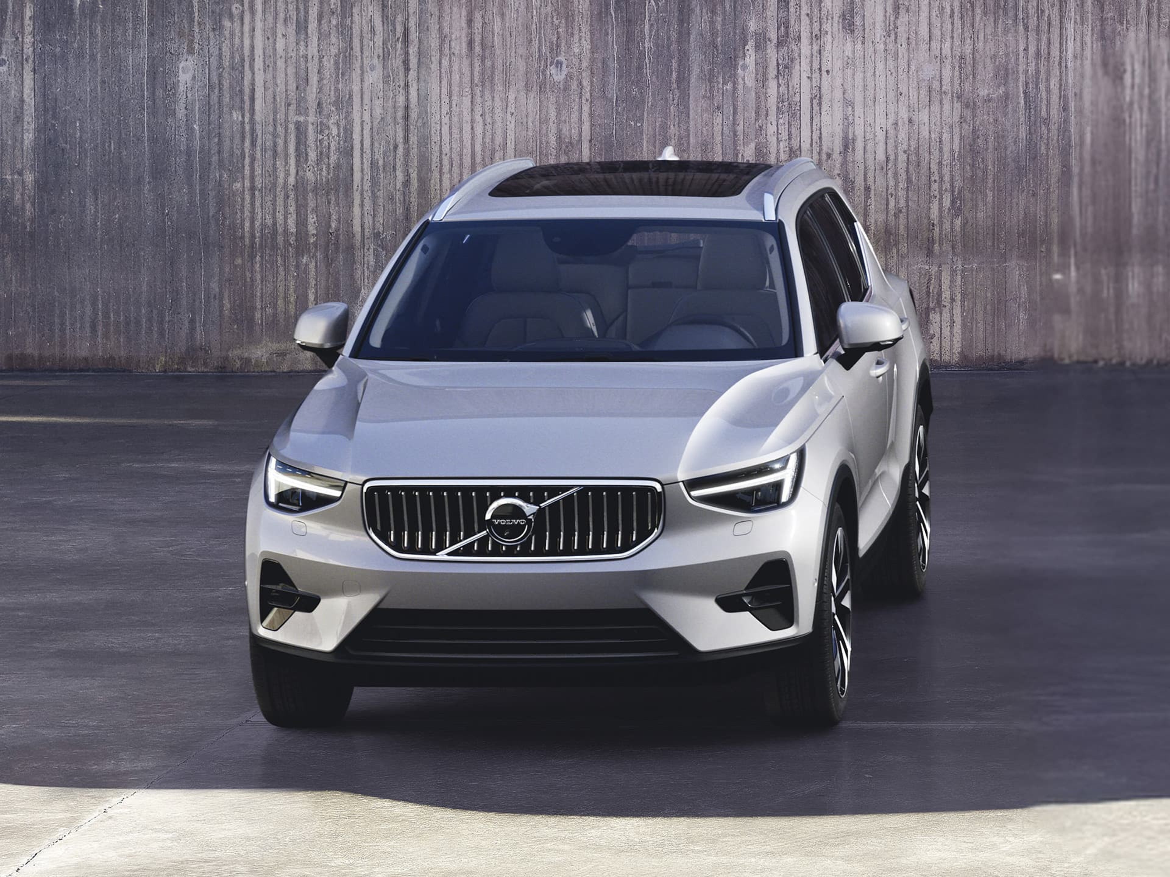 Vue de face d'un SUV compact Volvo XC40 de couleur argent, garé devant un mur en béton.