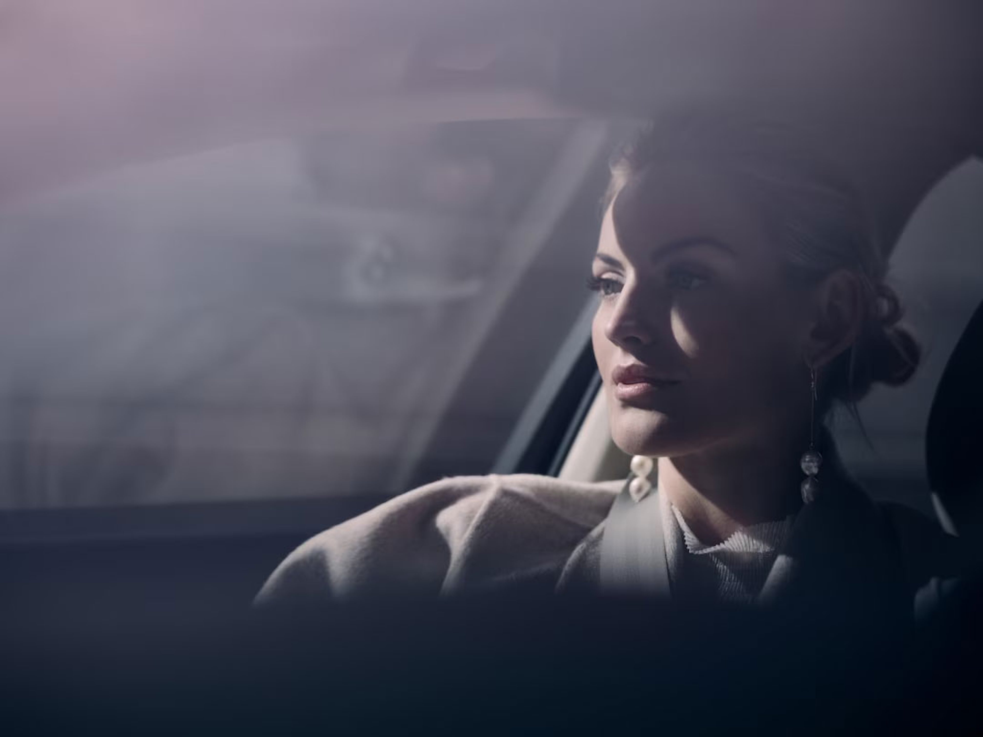 Femme assise dans une voiture, regardant par la fenêtre.