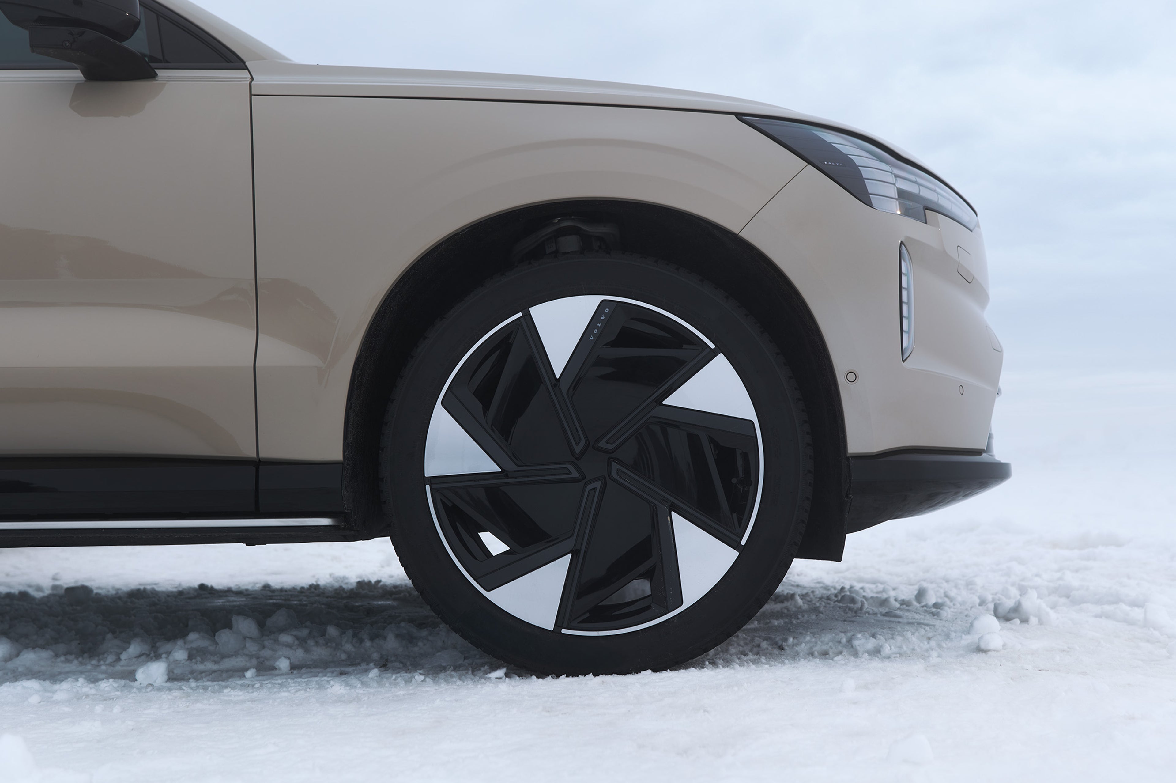 Fronten af en Volvo EX30 med komplette vinterhjul, inklusiv dæk og fælge, står parkeret i sneen.