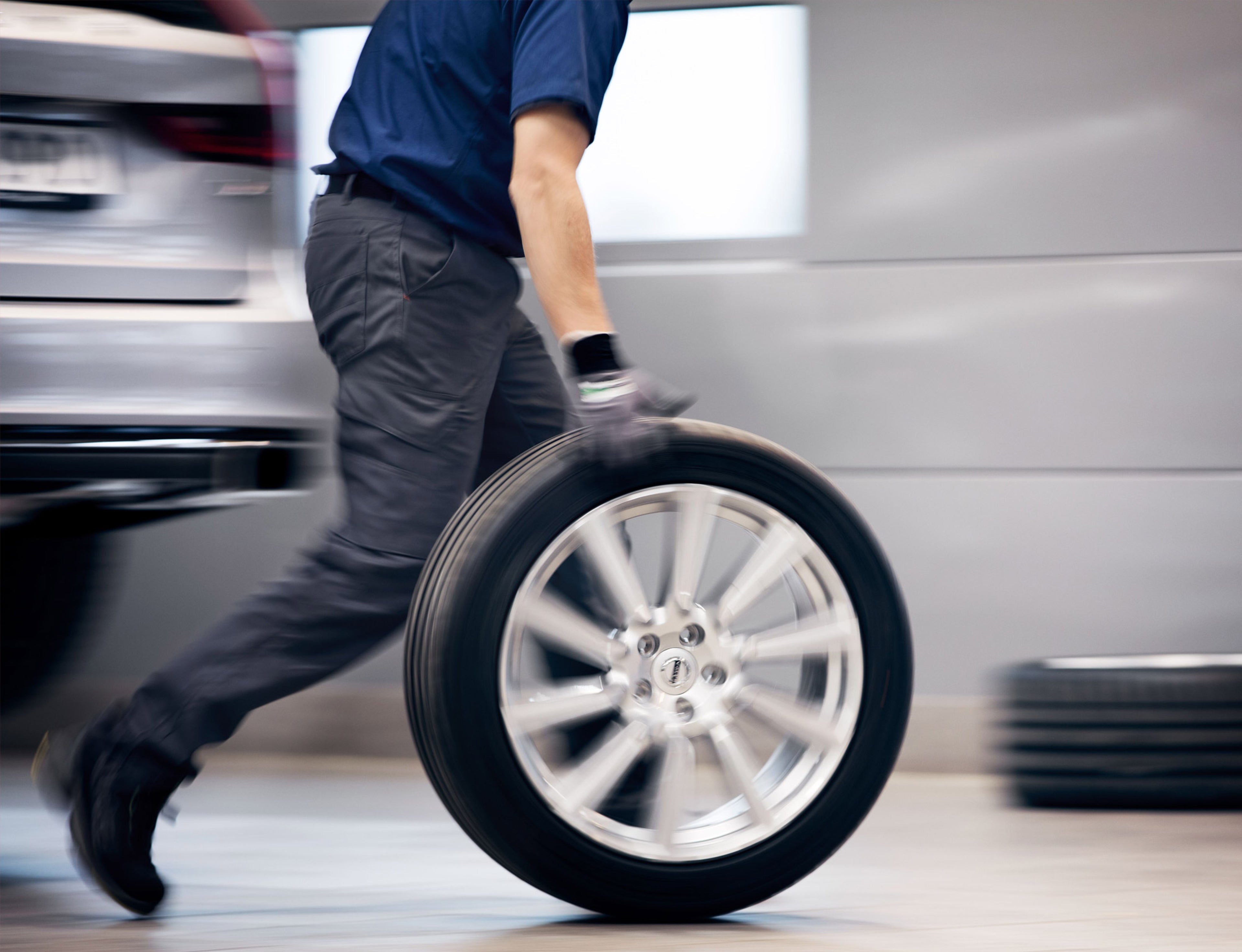 Een Volvo-mechanieker rolt een band van een Volvo door de werkruimte.
