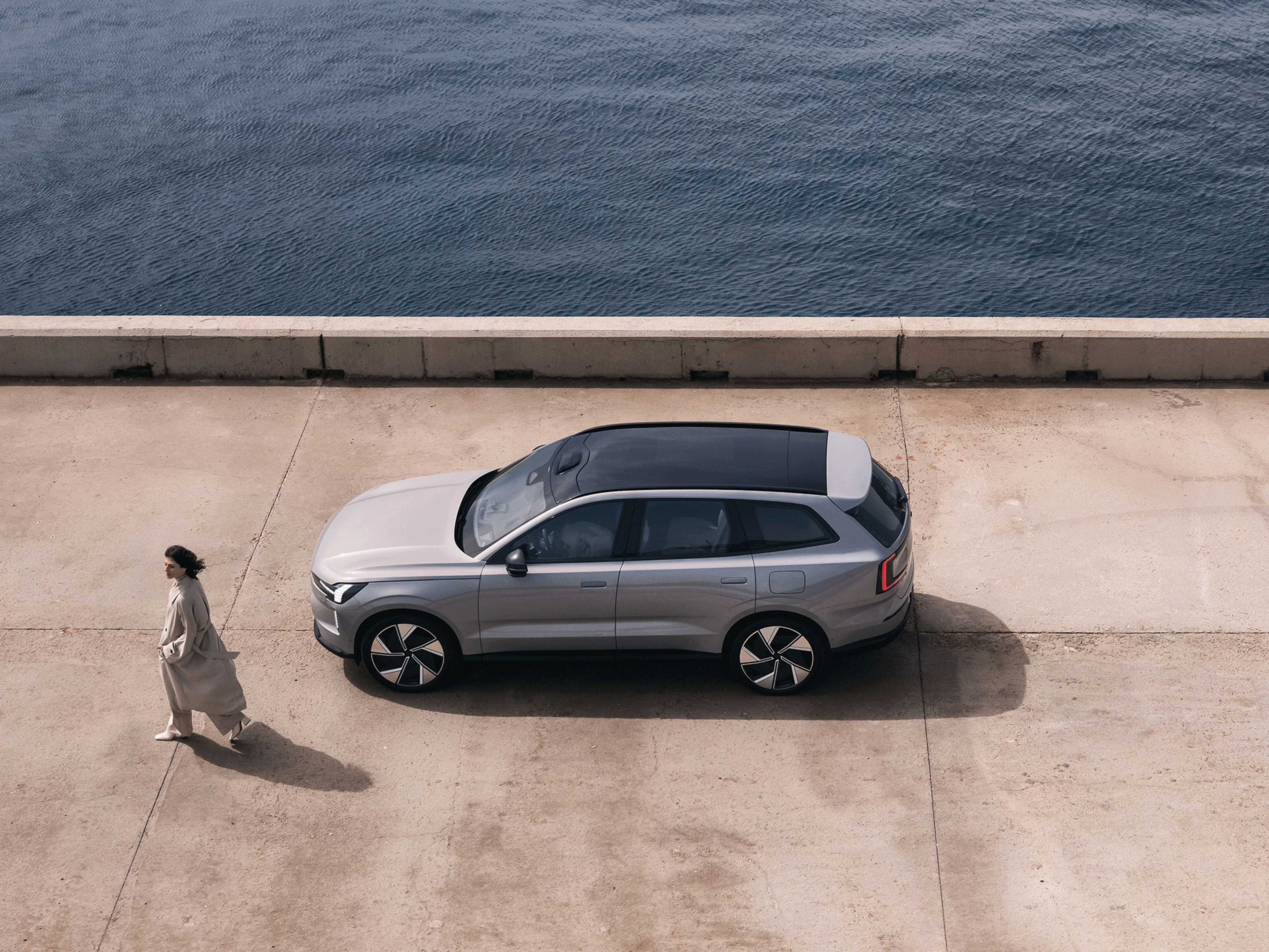 Eine Frau läuft neben einem Volvo EX90.