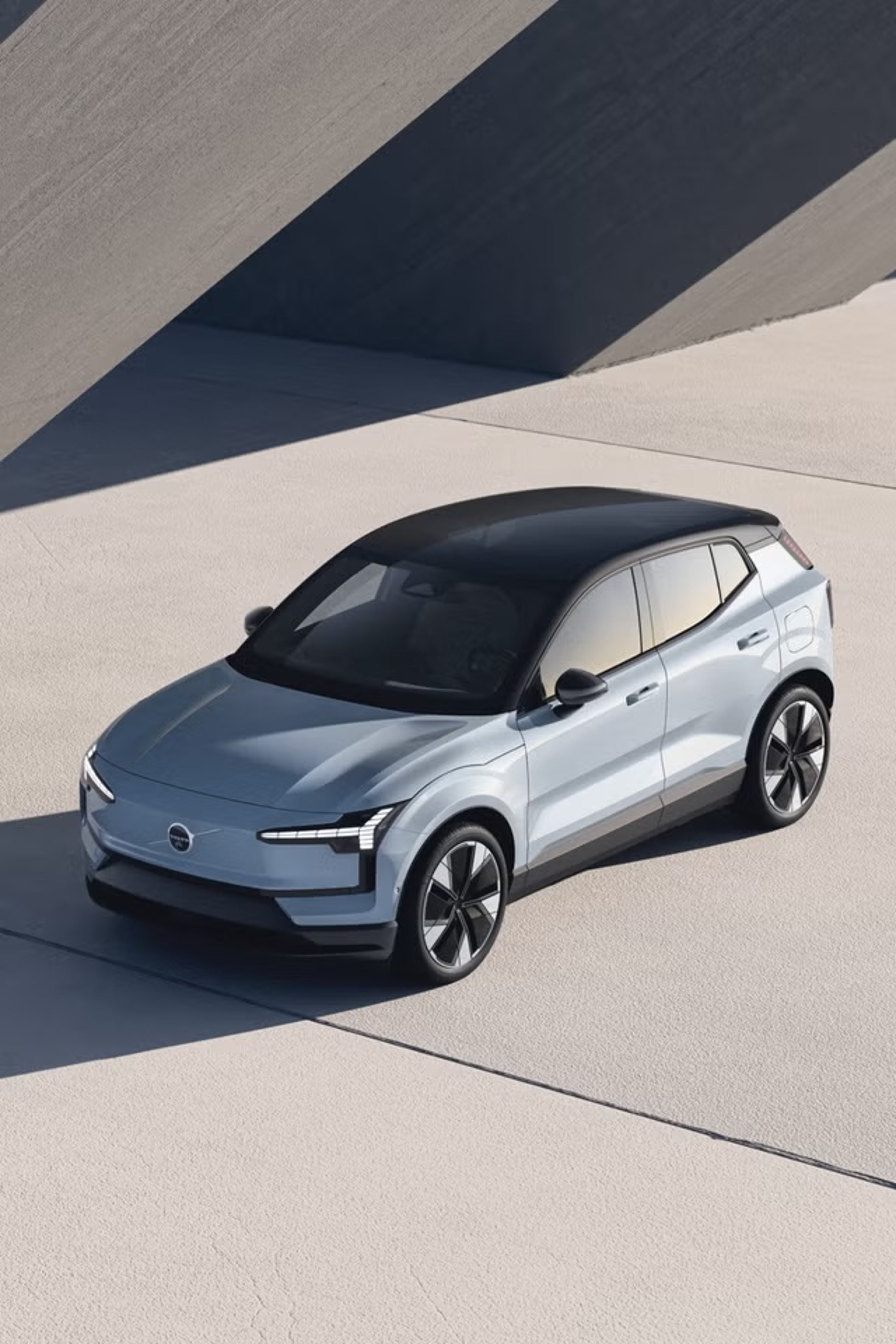 Volvo XC90, EX30 i XC60 SUV vozila parkirana jedno pored drugog u zalazak sunca, s planinama u pozadini.