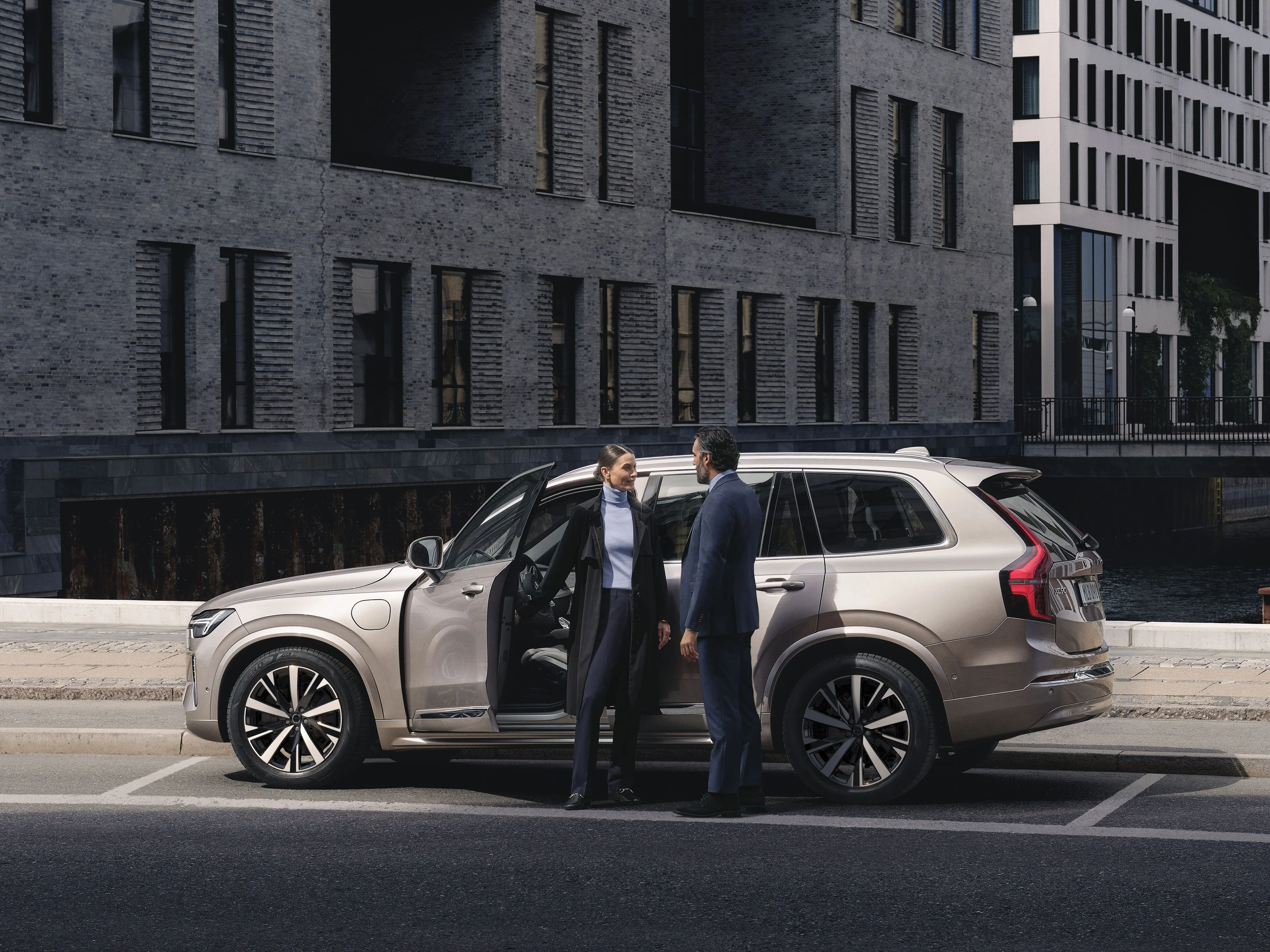Zwei Menschen stehen vor einem Volvo XC90 in der Farbe Sand Dune.