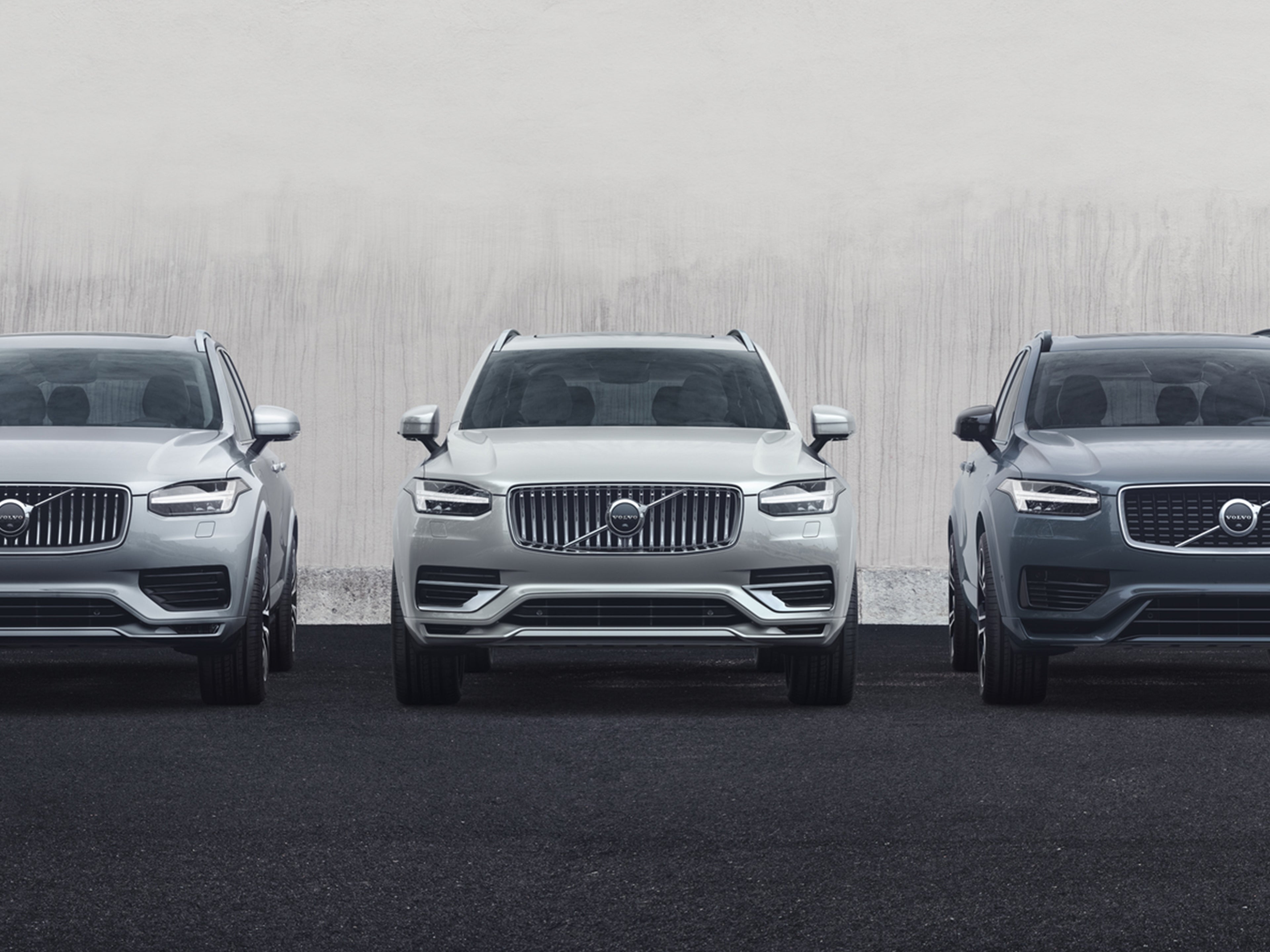 Harmaa, valkoinen ja tummanharmaa Volvo hybridiautot rivissä.