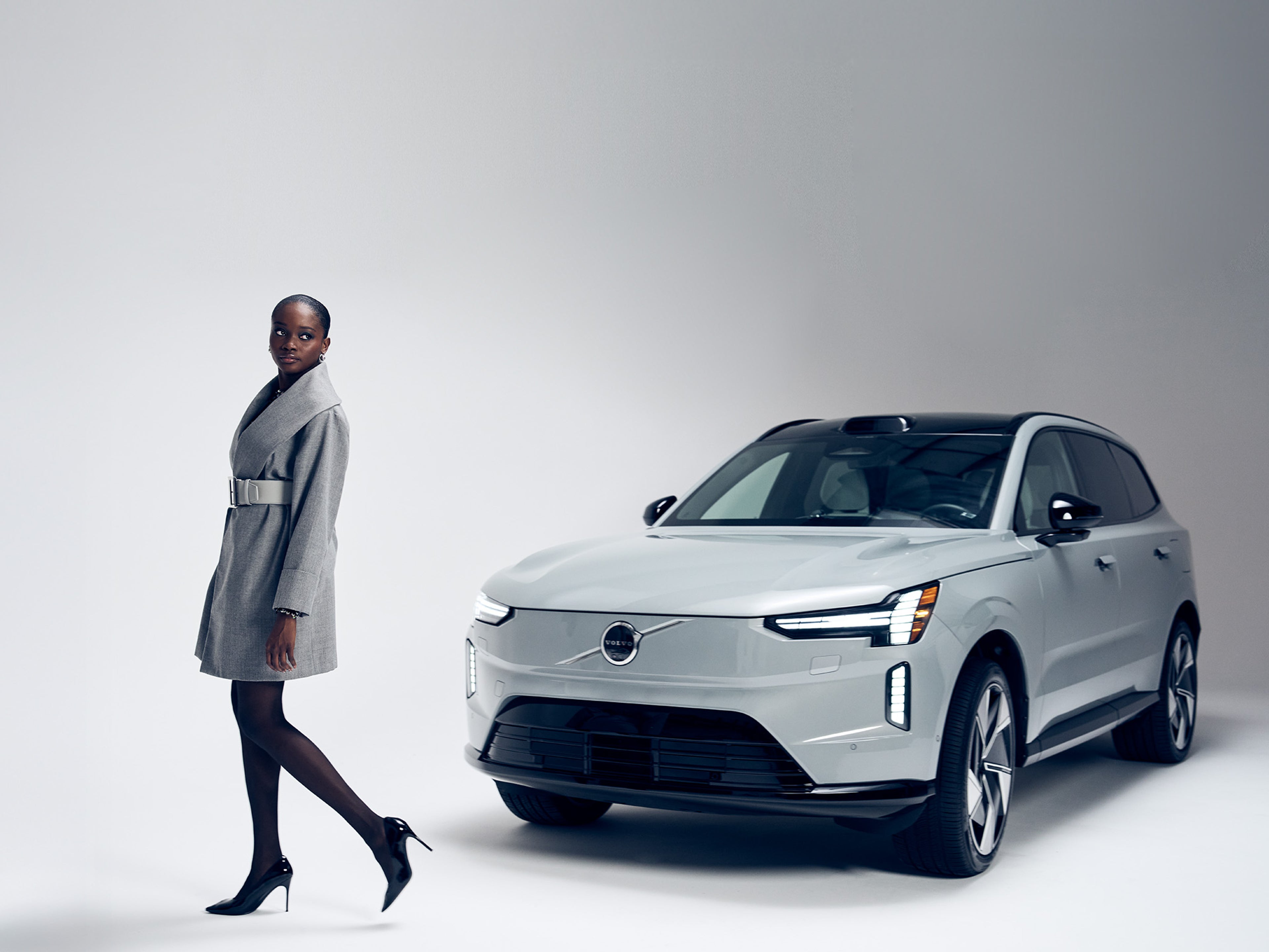 Woman wearing Sergio Hudson Belt next to Volvo EX90 SUV