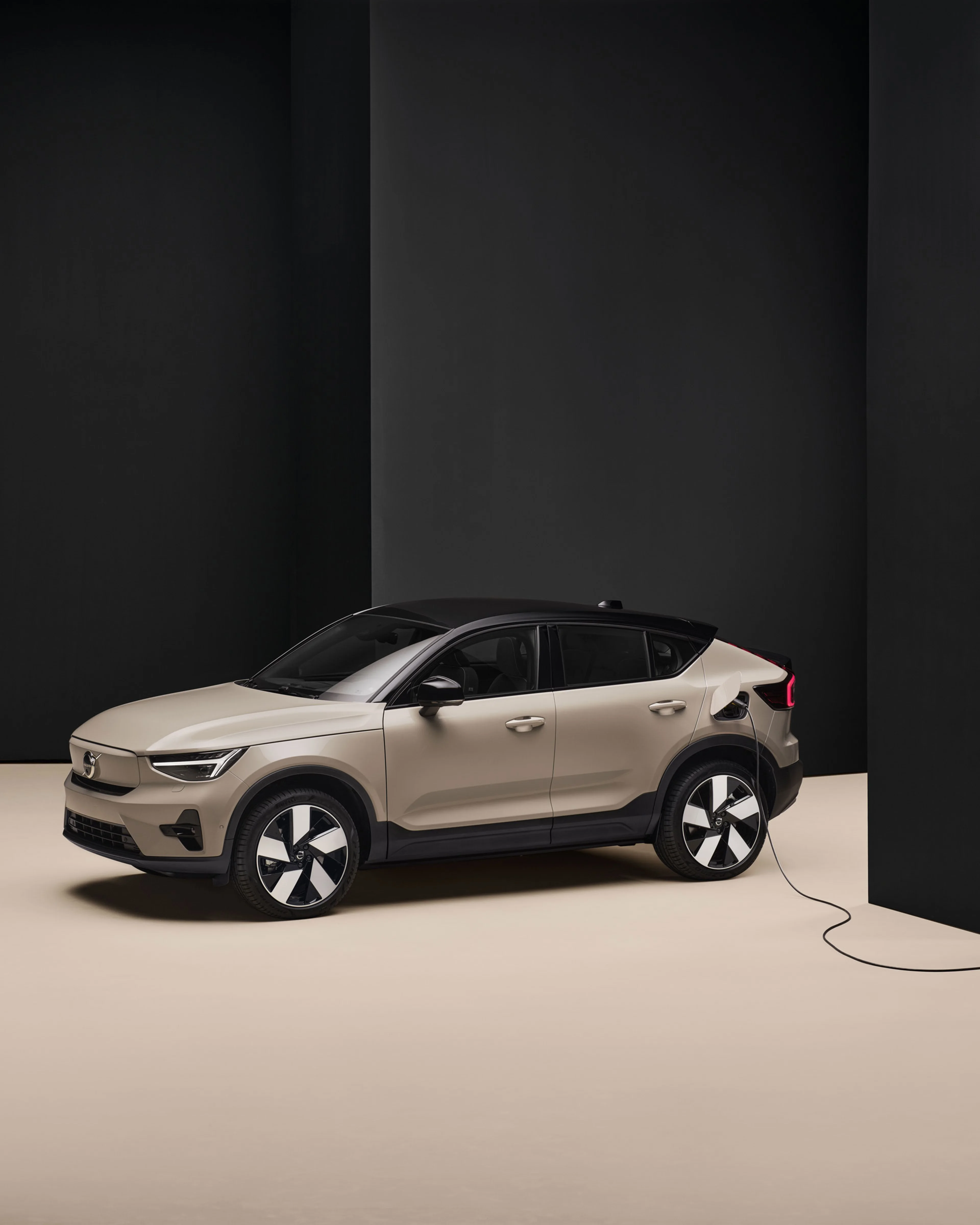 Volvo EC40 beige branché à une borne de recharge dans une pièce minimaliste noire et beige