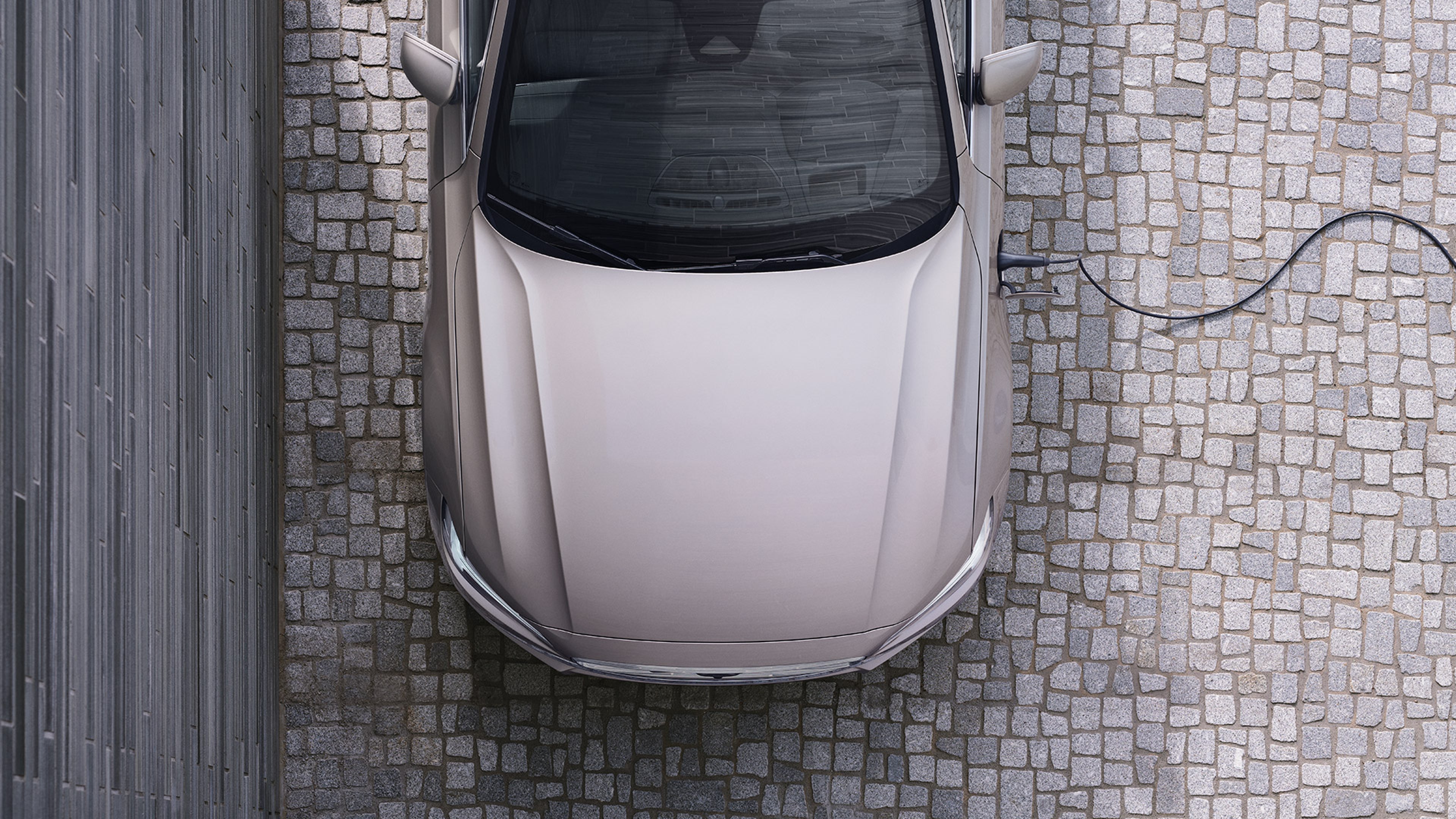 Lataukseen kytketyn Bright Dusk -värisen Volvo V90 lataushybridiauton keula ylhäältäpäin kuvattuna.