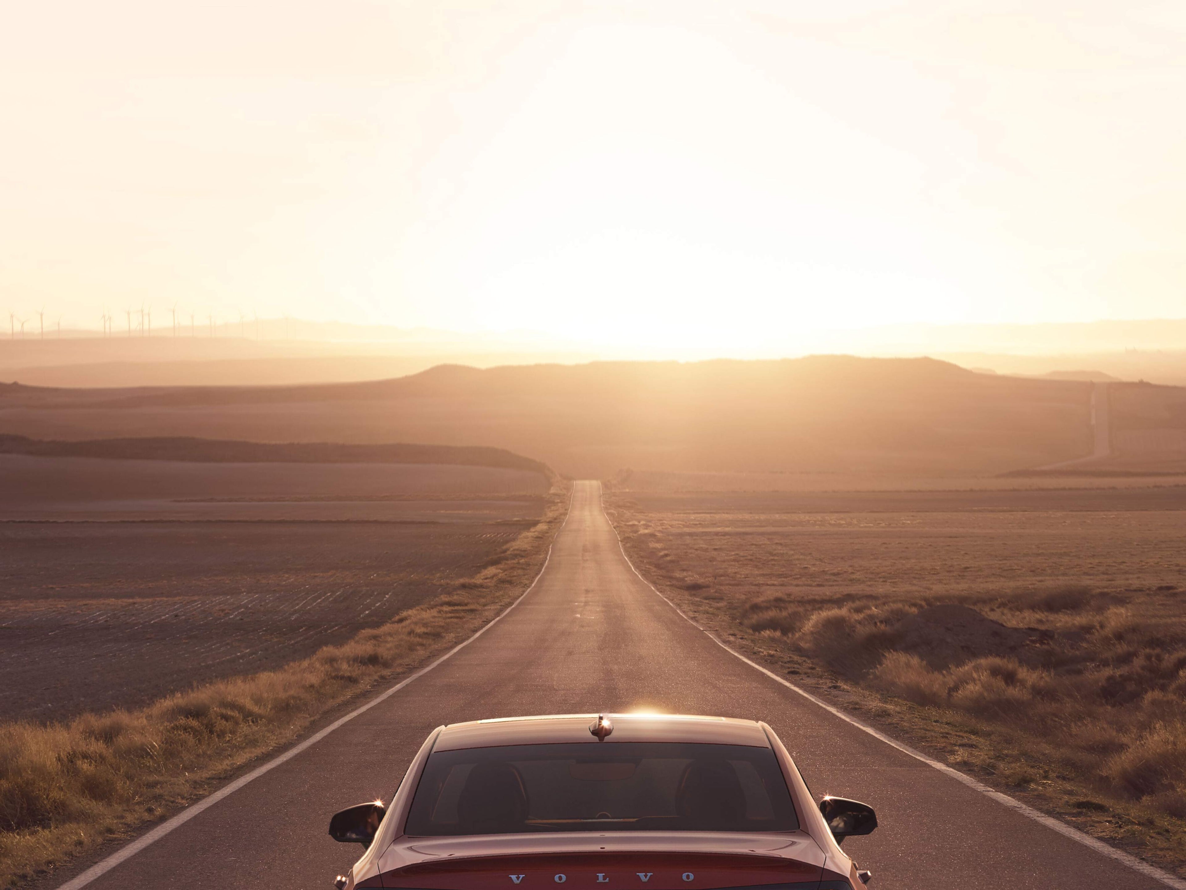 Punainen Volvo ajaa kohti auringonlaskua.