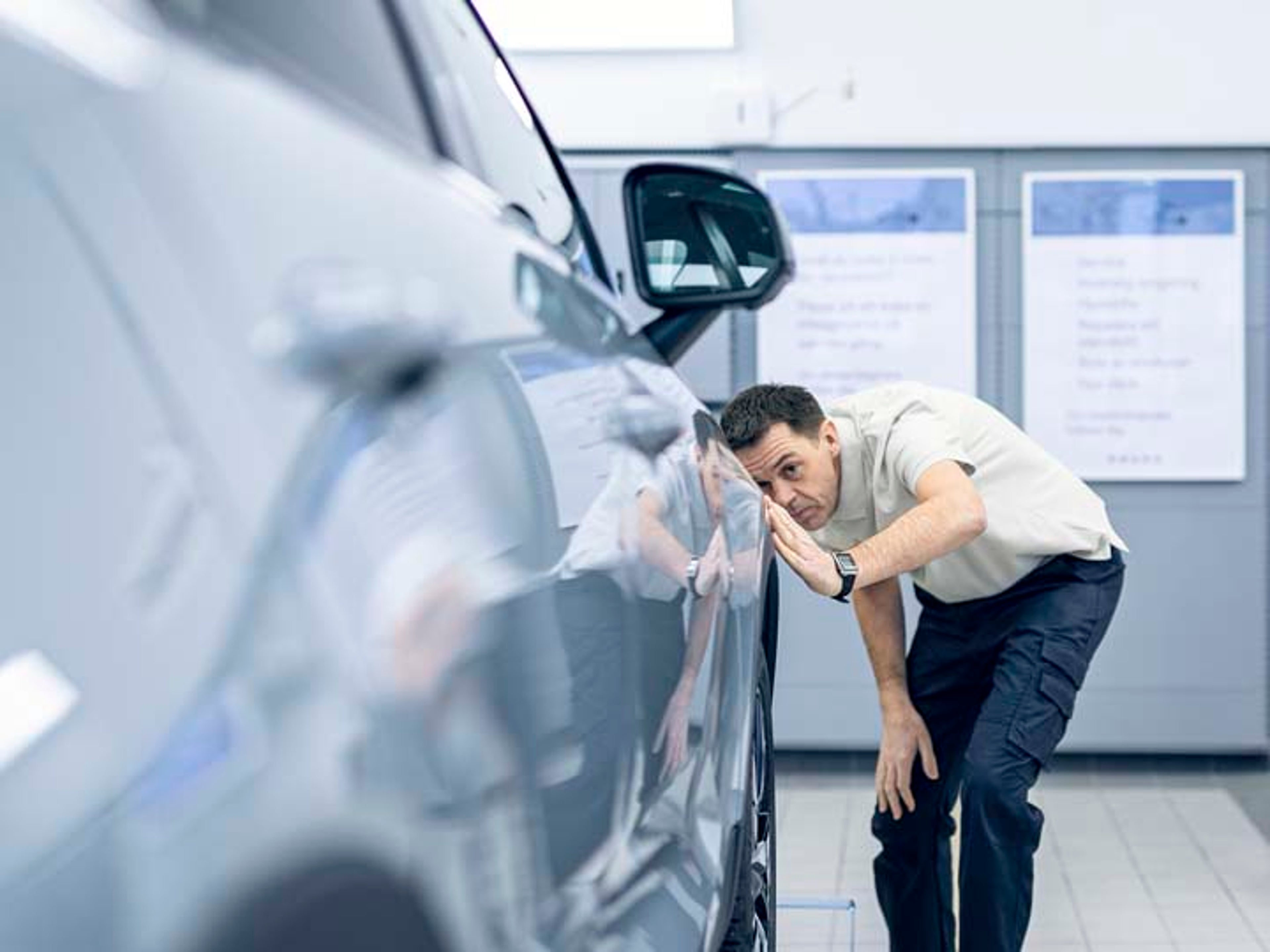 Un hombre haciendo una comprobación de carrocería de un vehículo Volvo