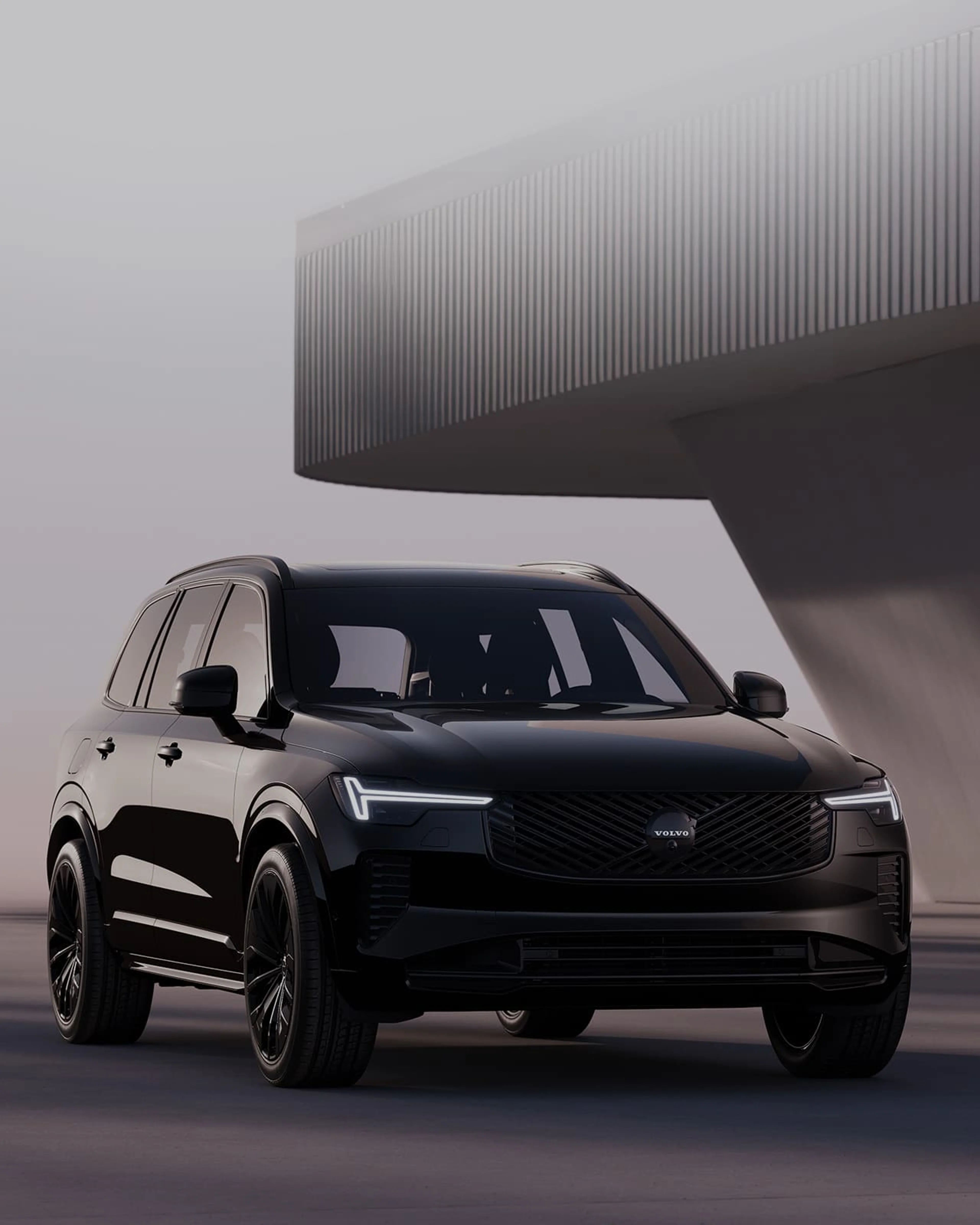 Vue de trois quarts avant de la Volvo XC90 Black Edition, garé devant un bâtiment moderne.
