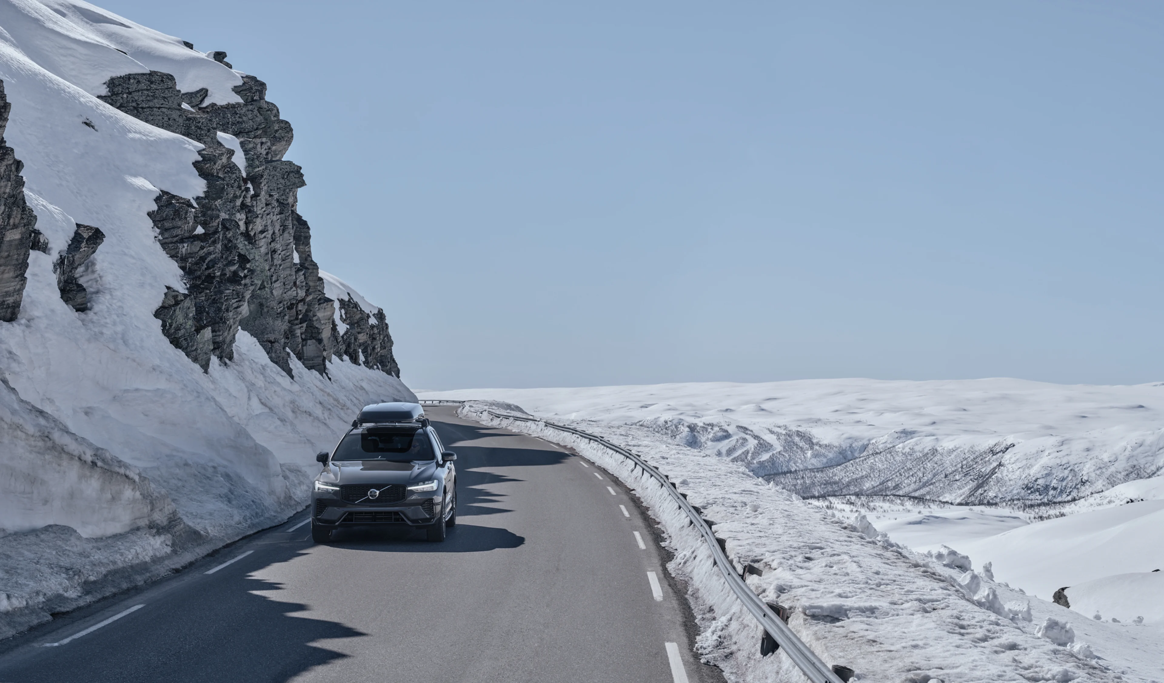 Вид спереди на Volvo XC60 на дороге с боксом на крыше
