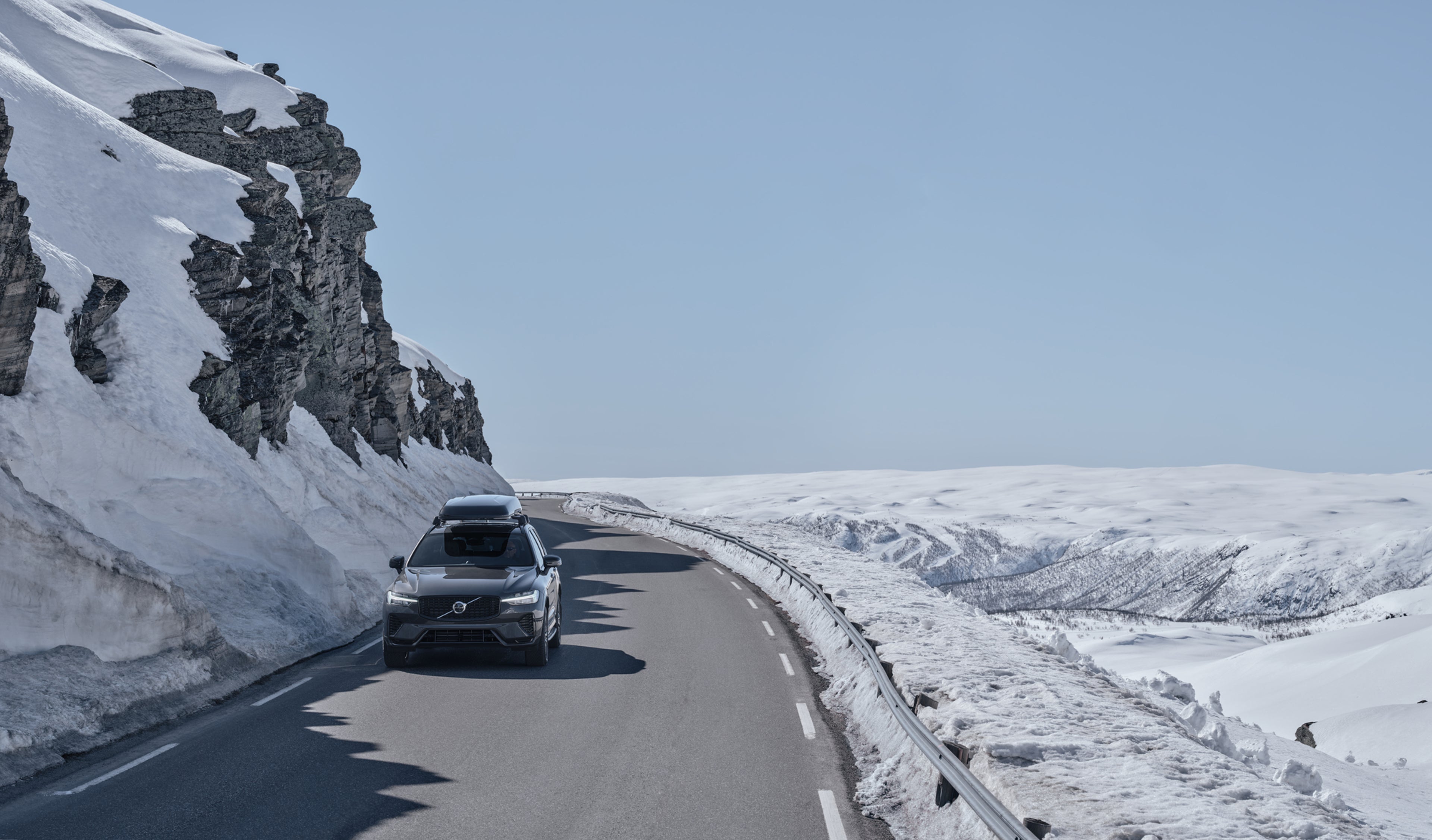 Vedere frontală a unui Volvo XC60 pe șosea cu boxa pe acoperiș