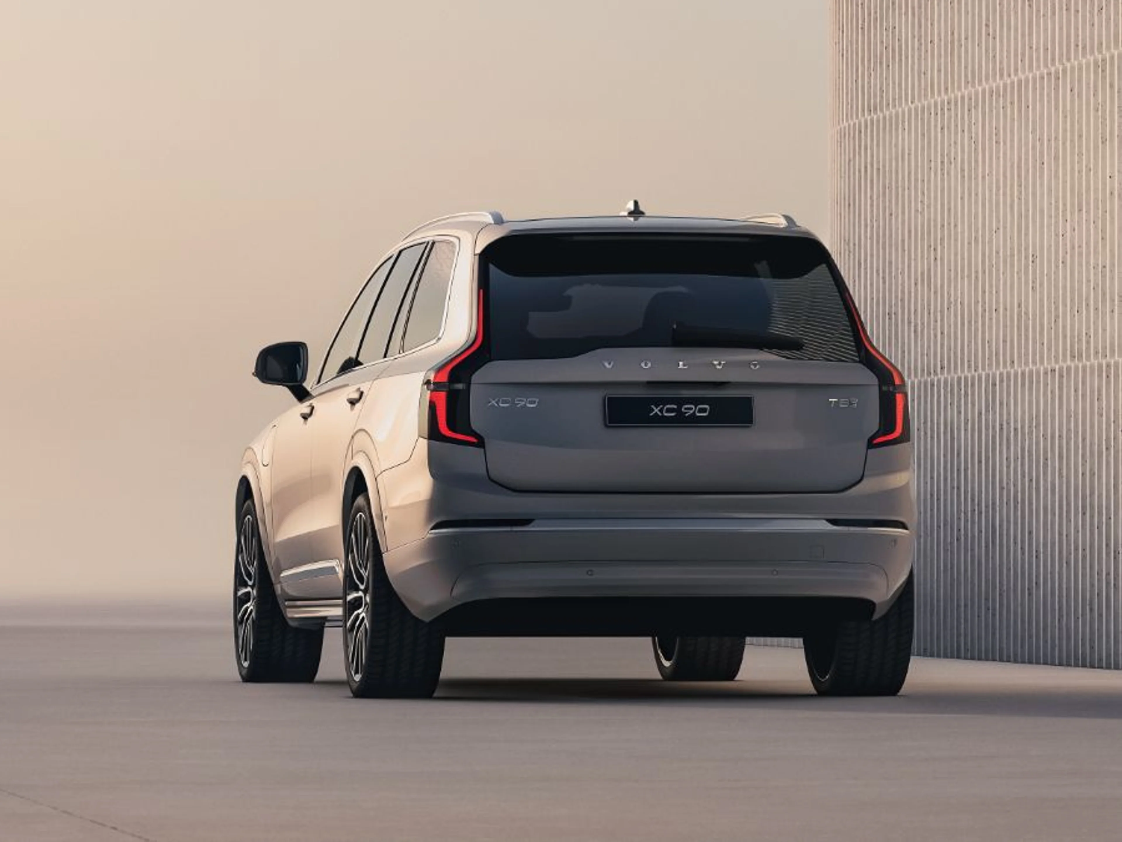 Volvo XC90 SUV u elegantnoj srebrnoj boji, parkiran u prostranom krajoliku pod nježnim svjetlom, ističući njegovu sofisticiranost i snažnu prisutnost.
