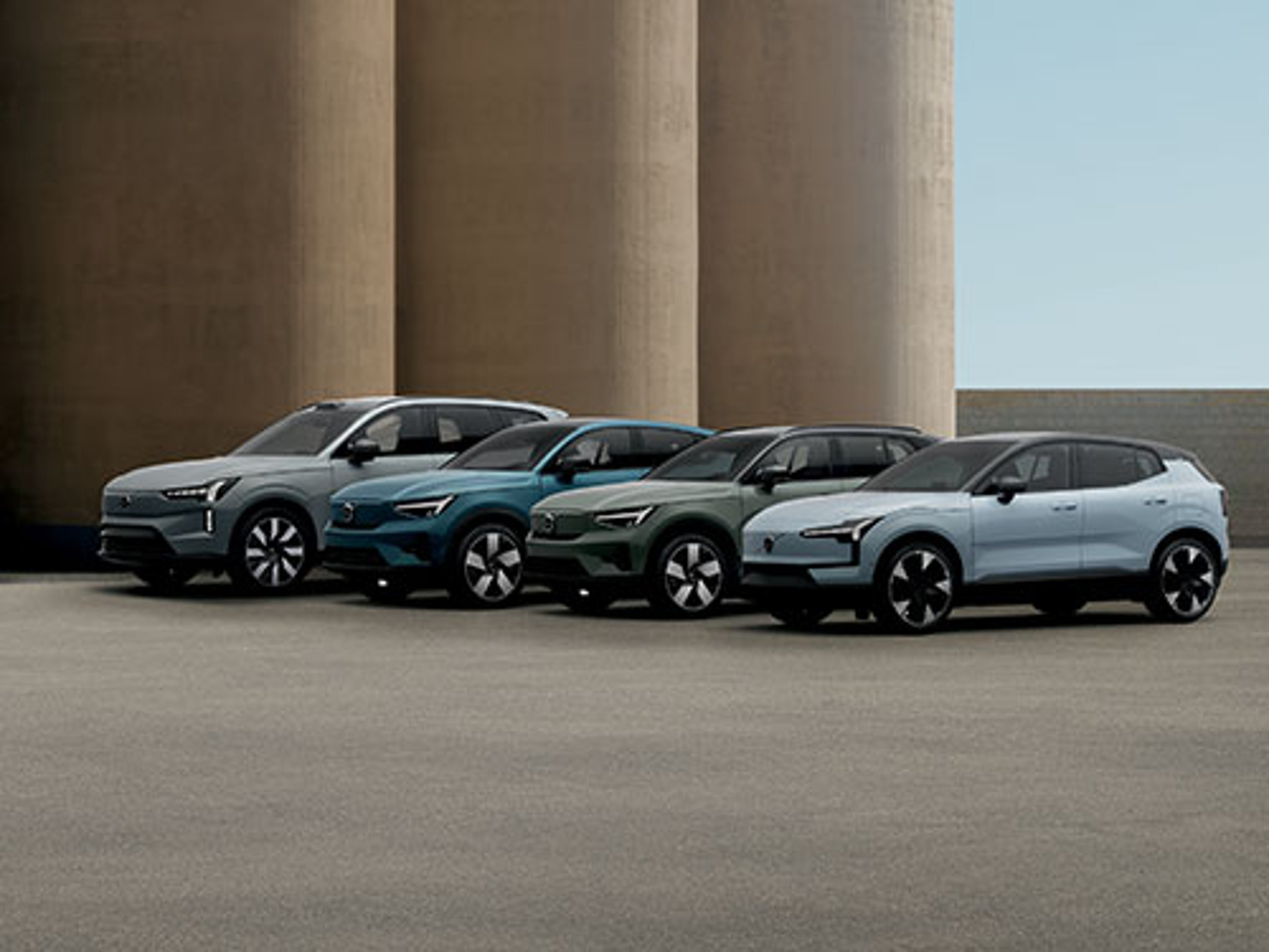 Quatre SUV électriques modernes de couleurs variées garés dans une zone industrielle en béton