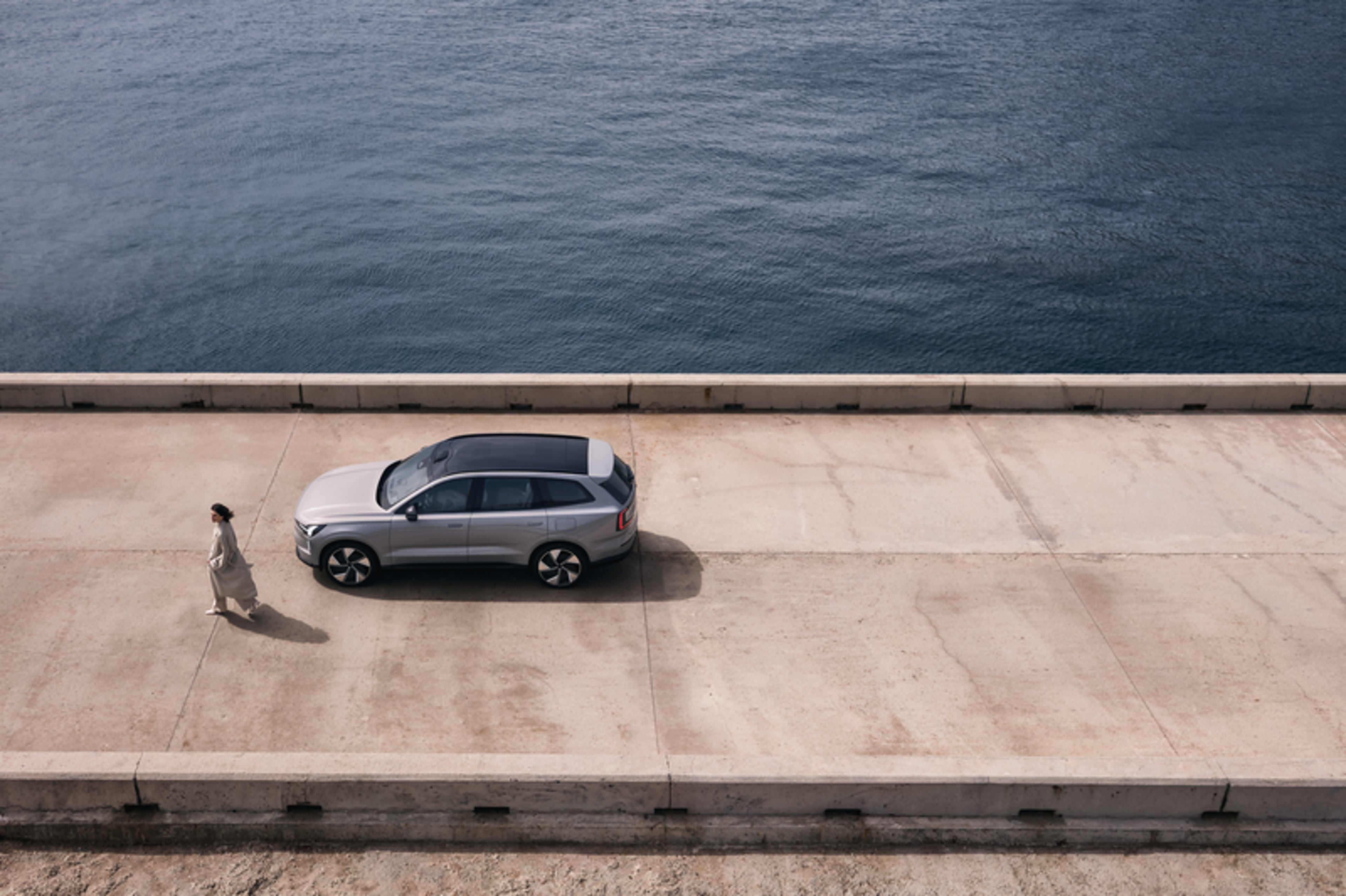 Egy hölgy egy Volvó mellett a tengerparton