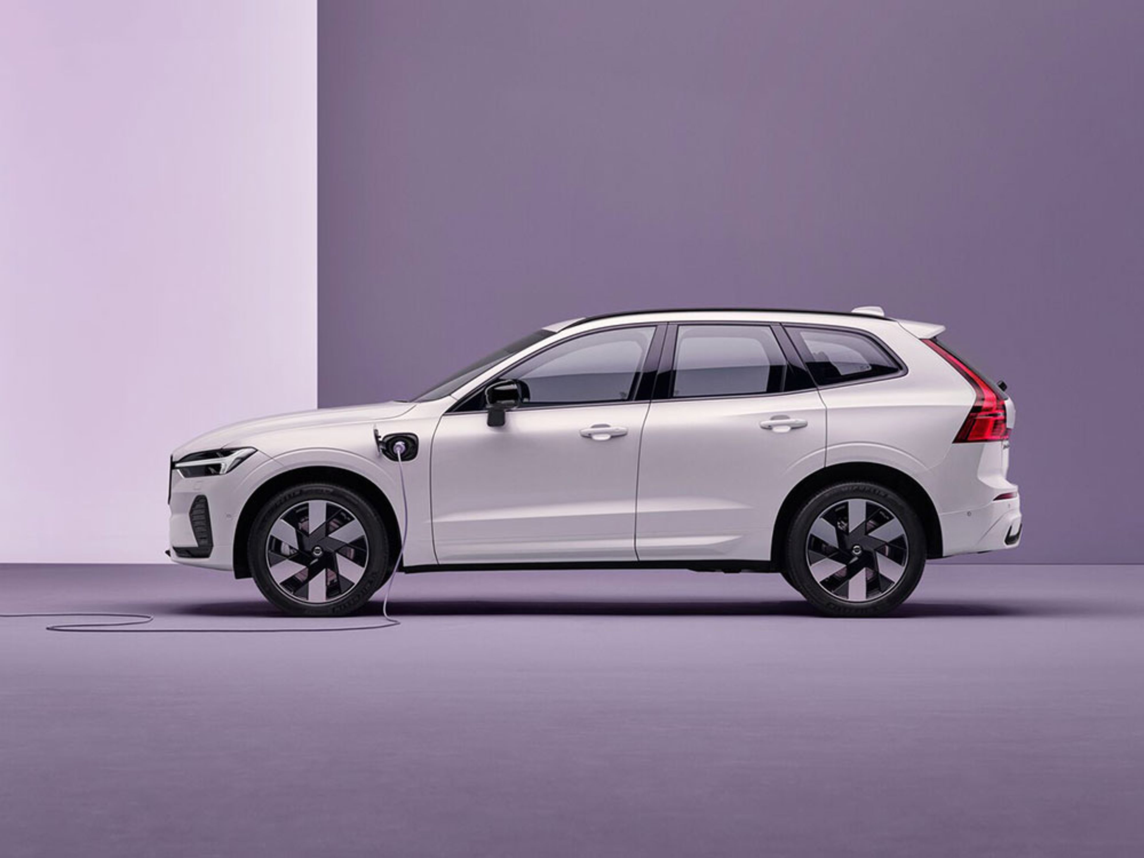 Volvo XC60 blanc branché à une borne de recharge sur fond violet