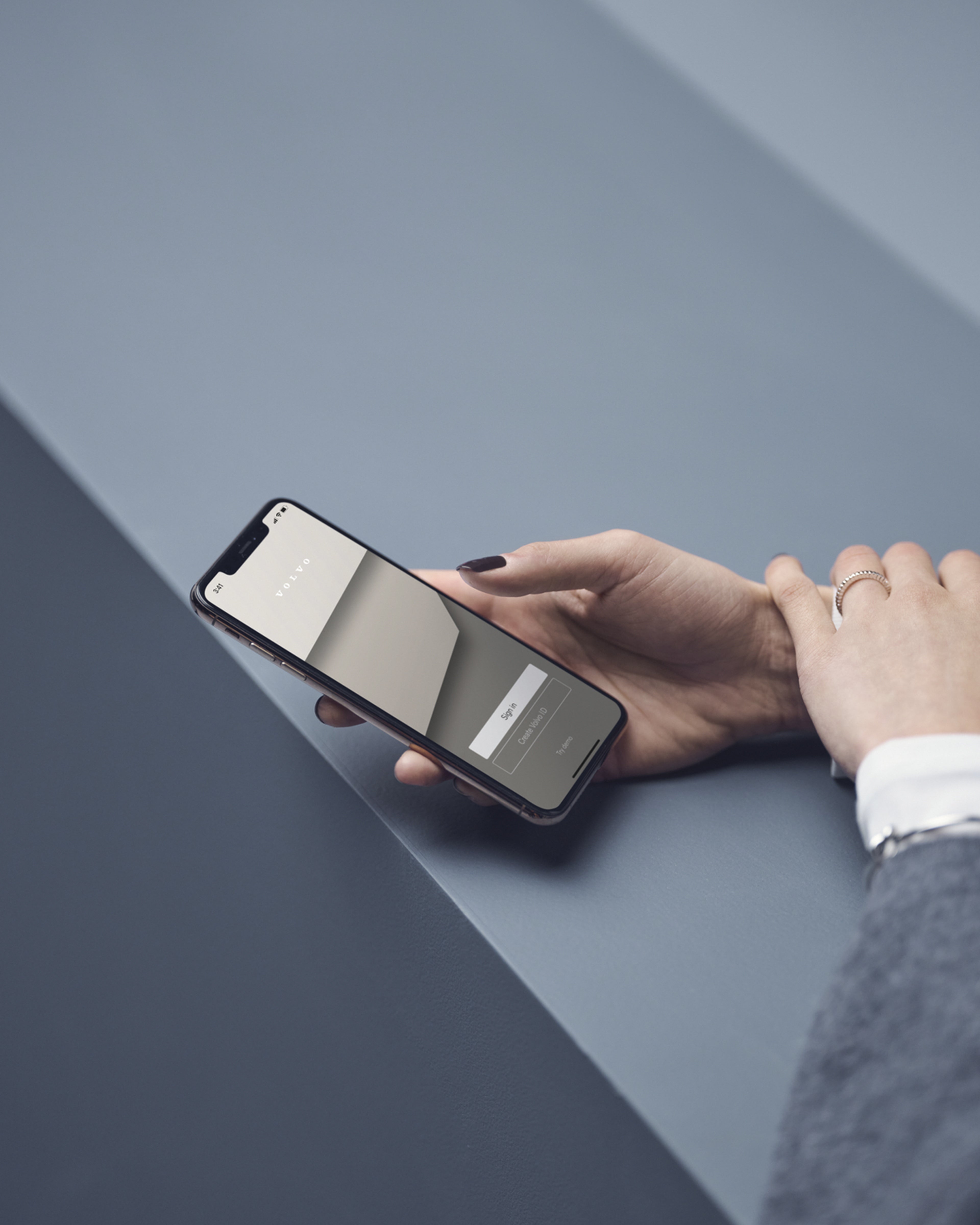 Una persona sosteniendo un teléfono celular sobre un fondo gris.