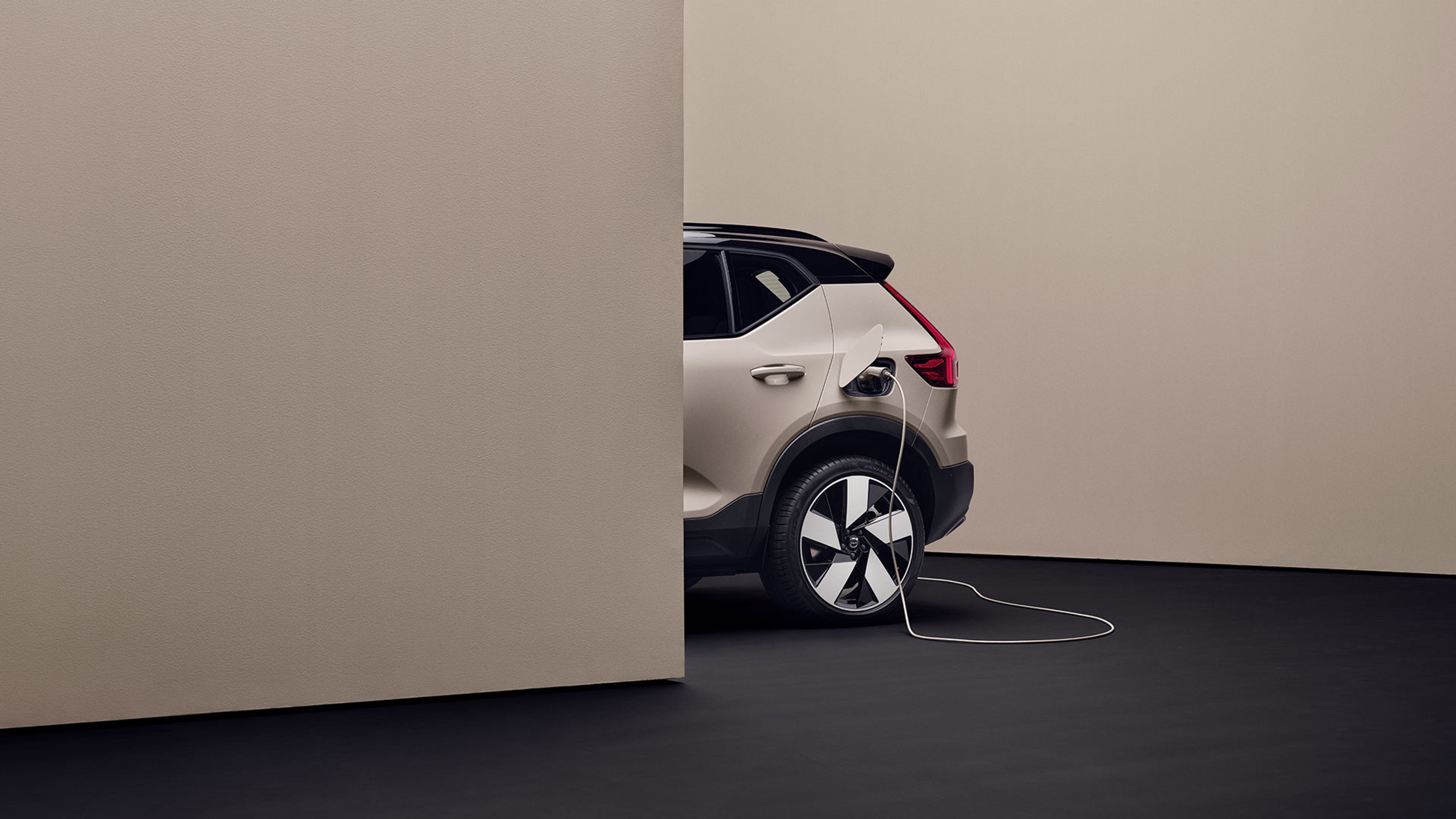 Vue tronquée de l’arrière d’un EX40 Sable Dune en charge dans un décor de studio moderne