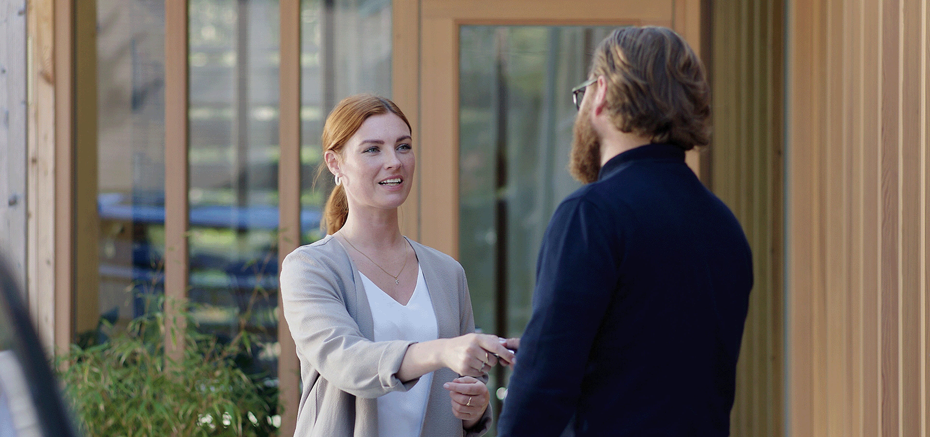 Ein Volvo Mitarbeiter übergibt einen Schlüssel an eine Volvo Kundin.