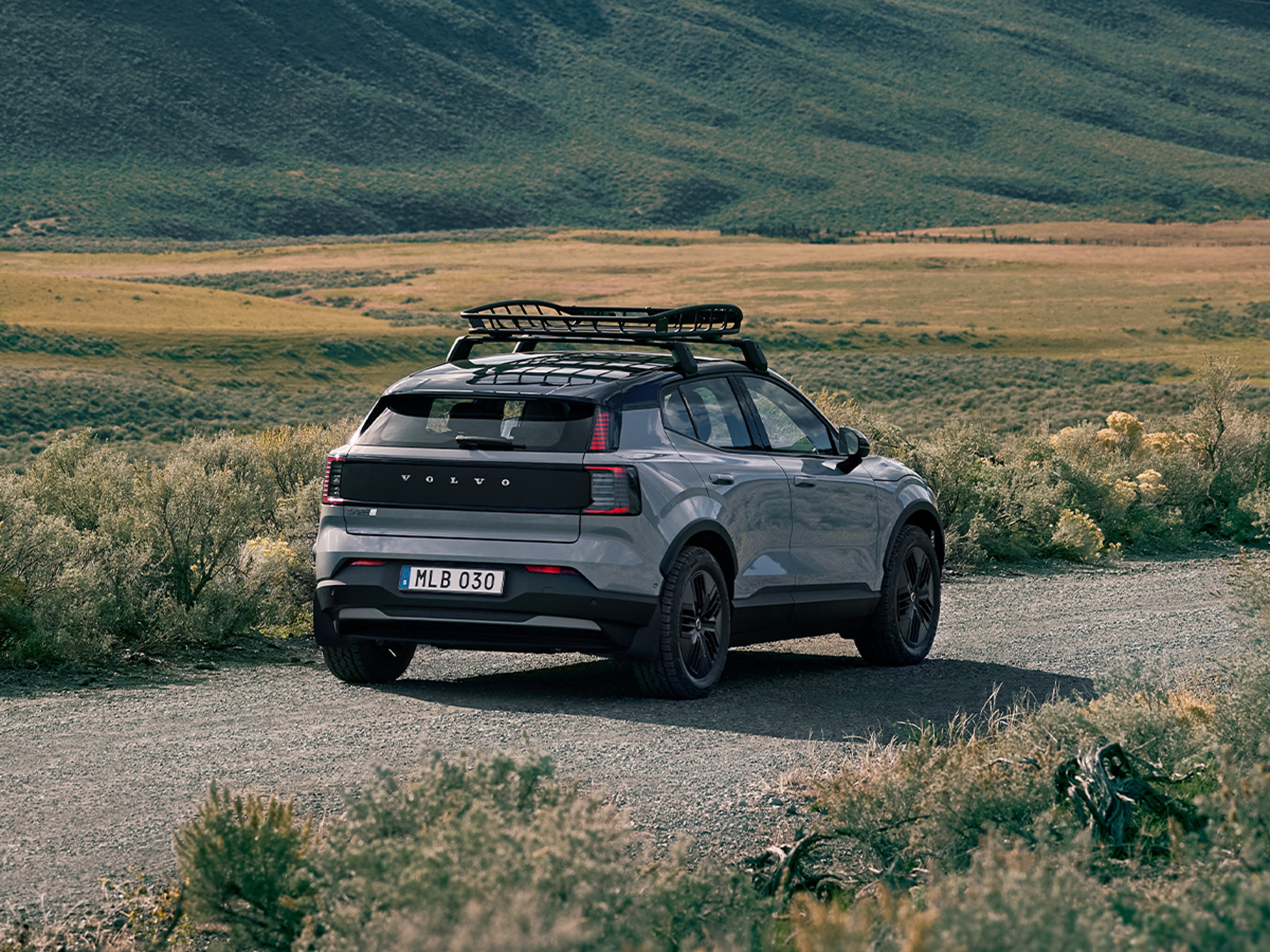 Volvo EX30 Cross Country med lastkorg på taket, snett bakifrån på en landsväg