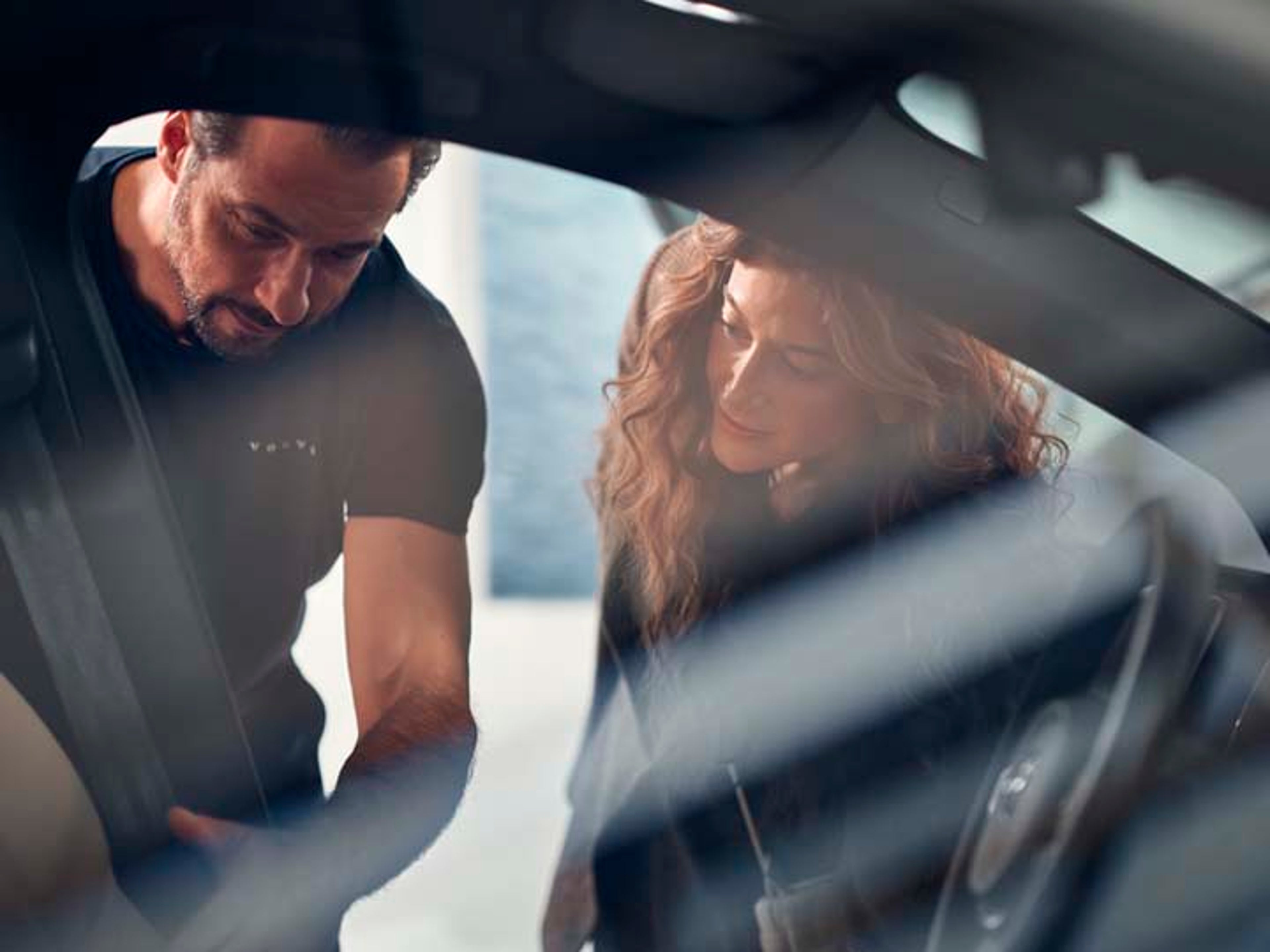 Un mecánico y una cliente mirando dentro de un vehículo Volvo