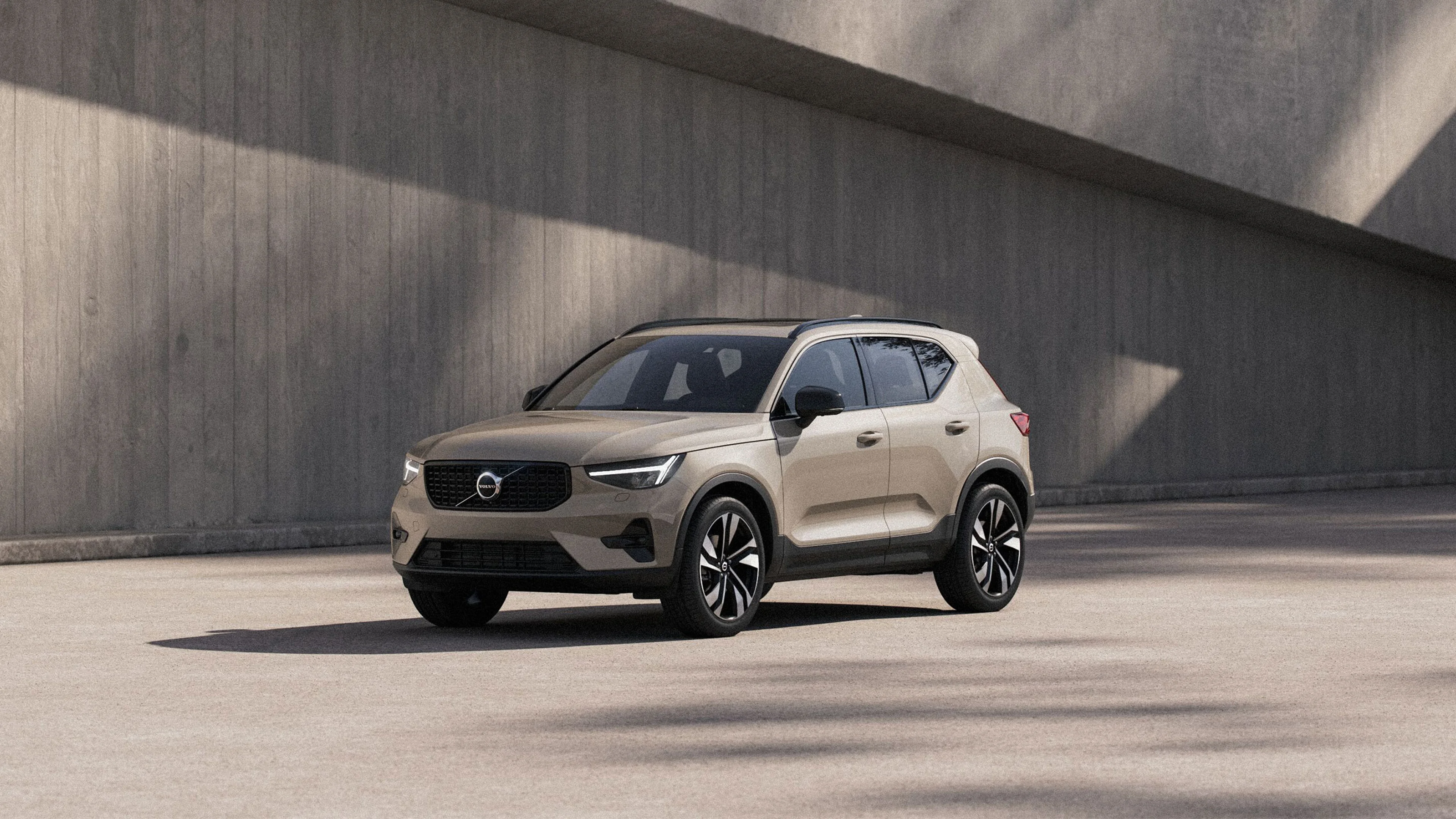 Volvo XC40 beige stationné en extérieur, avec un mur en béton en arrière-plan