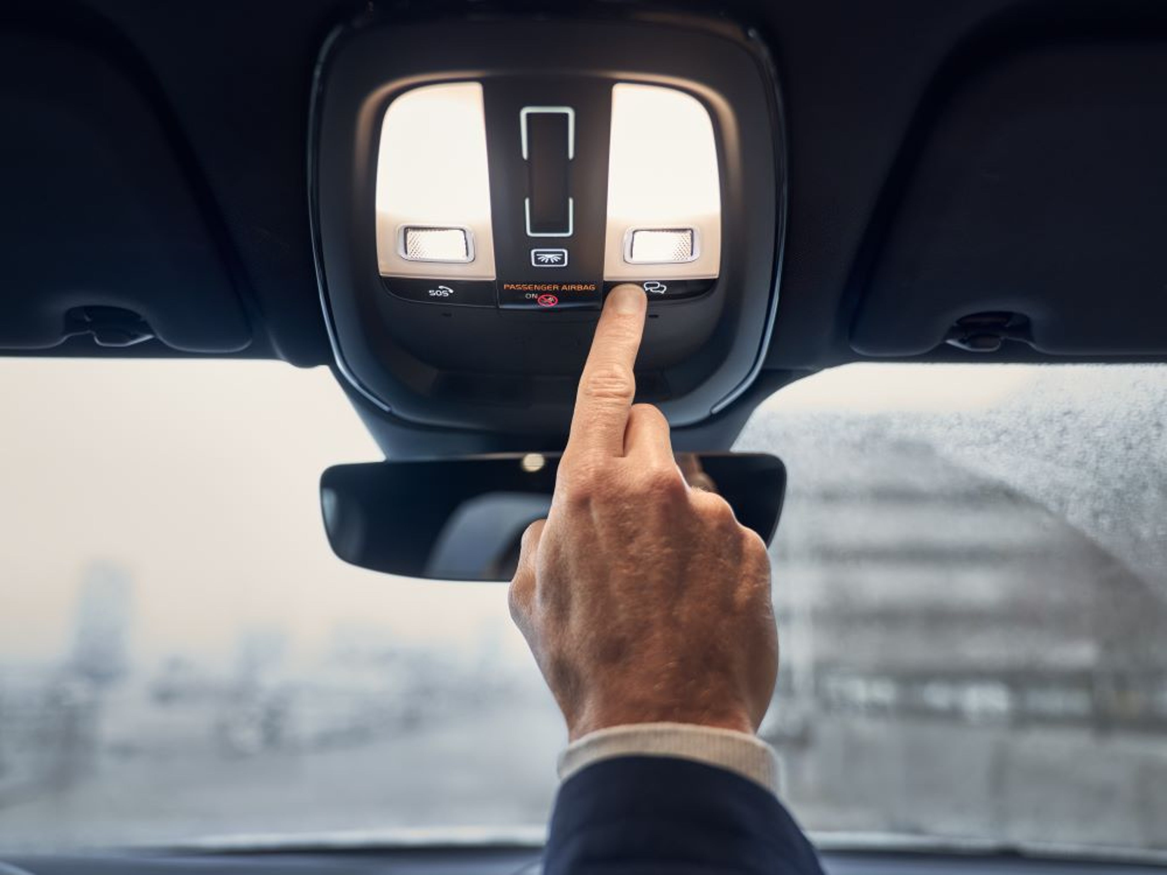 Person pressing button in overhead console in Volvo SUV